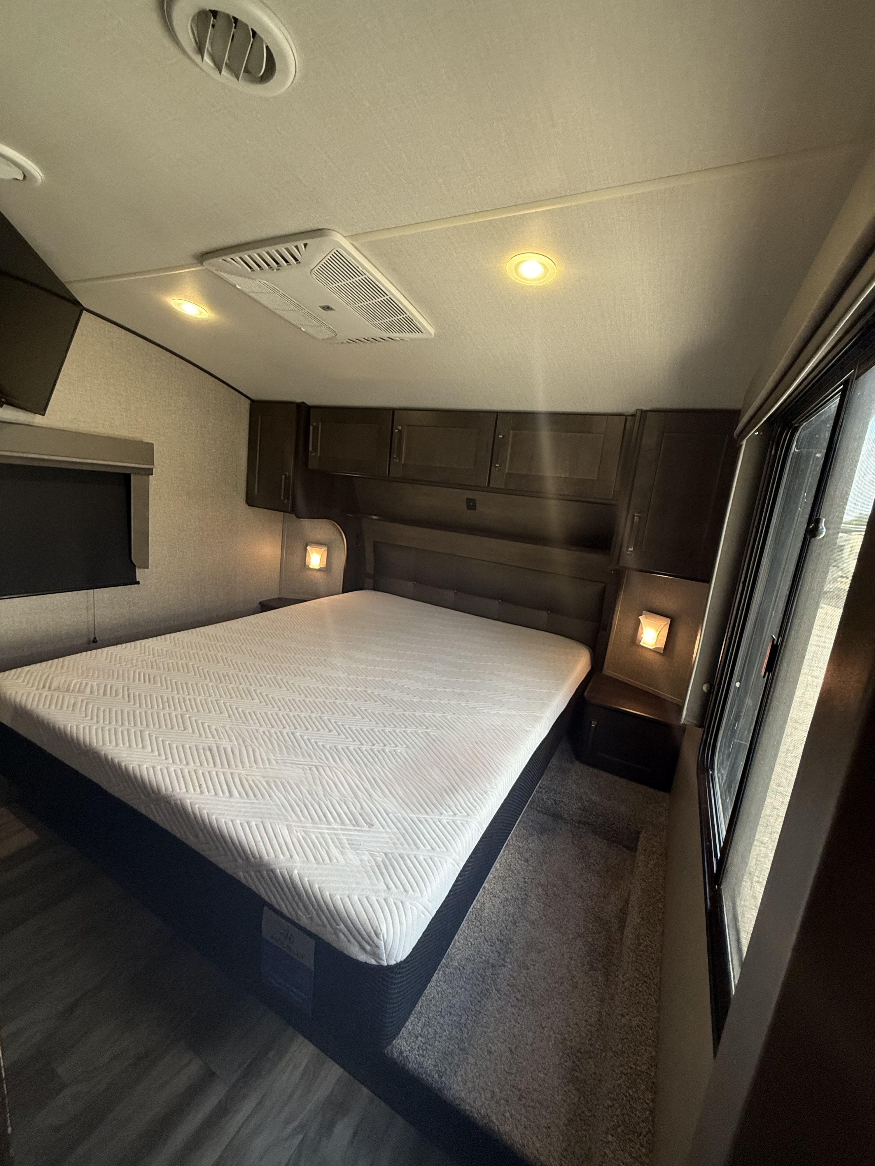 This RV rental offers a well-appointed bedroom with a comfy bed, overhead storage, and mood lighting.. Grand Design Reflection 2021