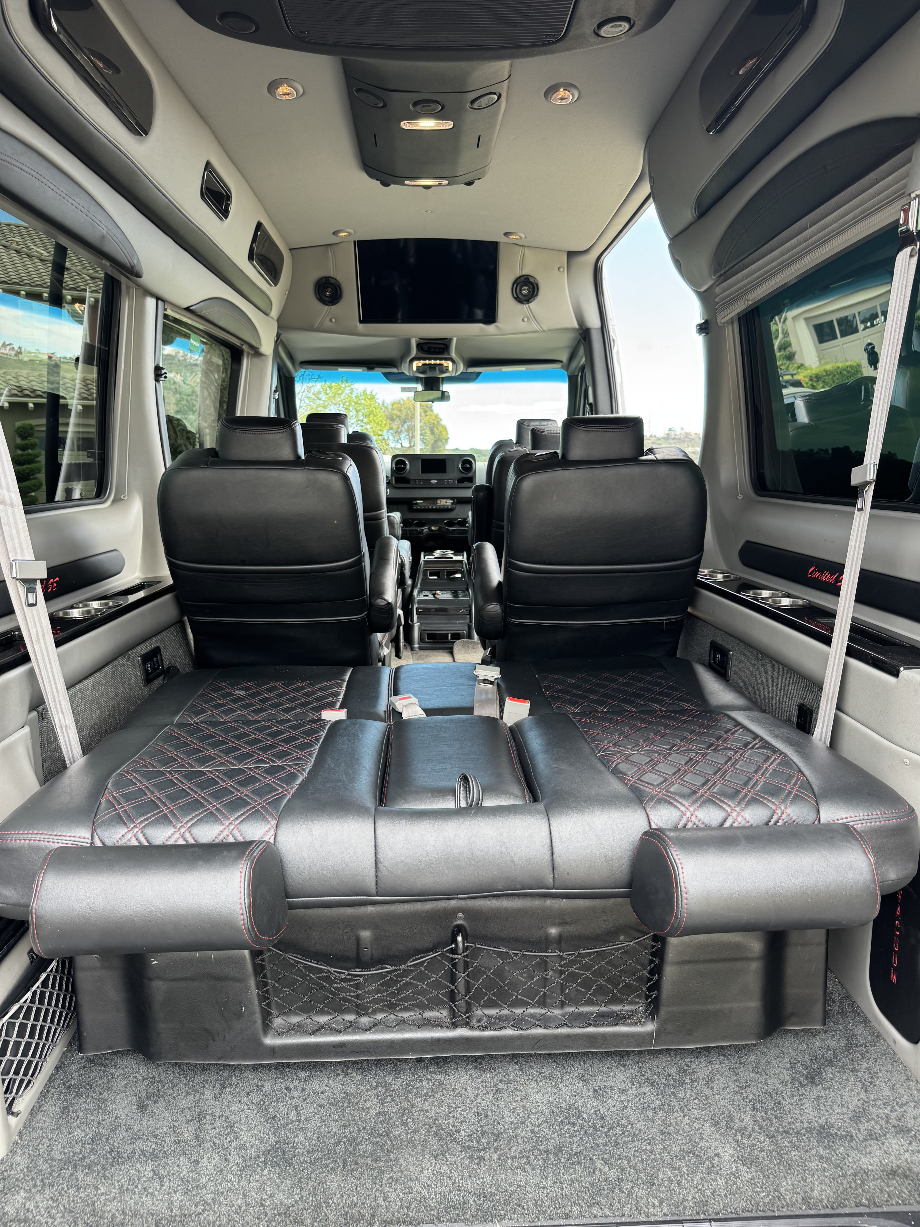 Luxury rv rental interior. Features plush black leather seats with red stitching, TV, and a convertible rear bed for comfortable travel.. Mercedes Benz Sprinter 2500 4x4 2019
