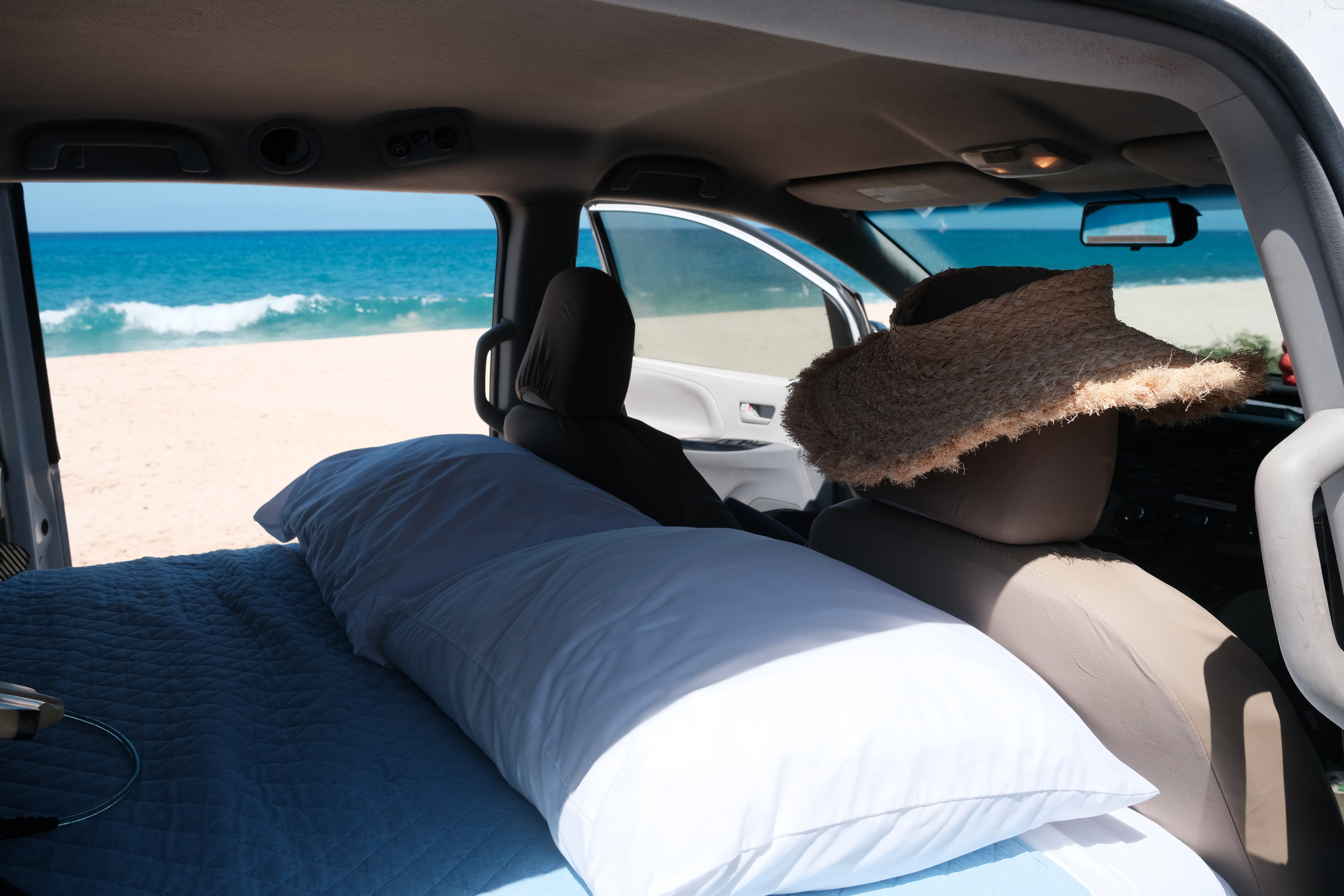 RV rental bed with an ocean view. Experience cozy van life camping right by the beach, complete with pillows and blankets.. Toyota Sienna 2011