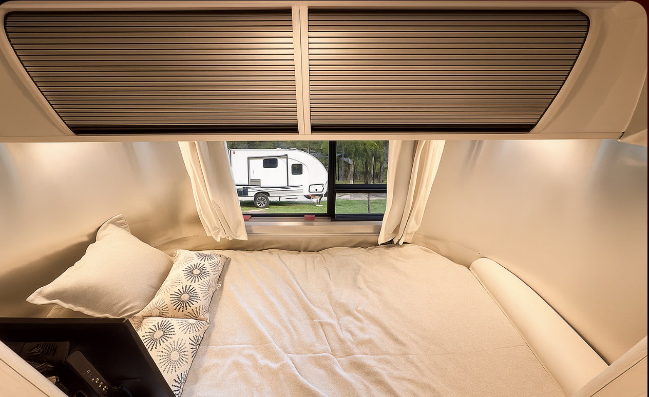 Cozy RV rental bedroom featuring a comfortable bed and a window view of another camper outside.. Airstream Bambi 2024