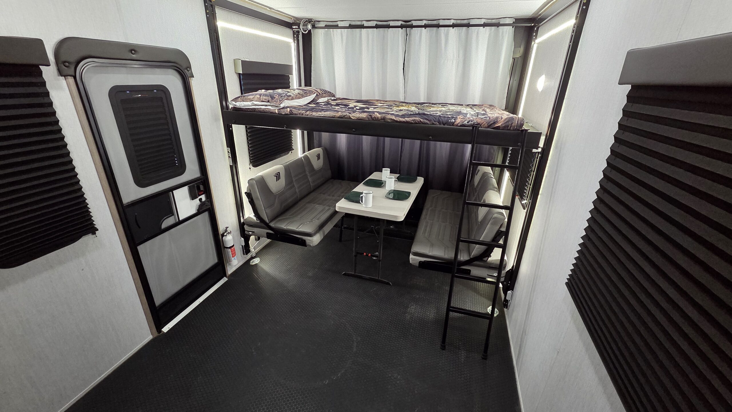 RV rental toy hauler interior with bunk bed, versatile dinette, and rugged floor. Ideal for camping adventures.. Grand Design Momentum 2023