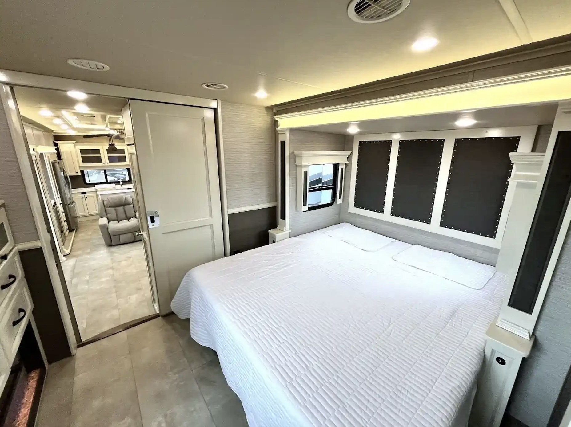 Relaxing RV rental bedroom featuring a spacious white bed, modern paneling, and access to living areas. Perfect for unwinding.. Vanleigh RV Beacon 2022
