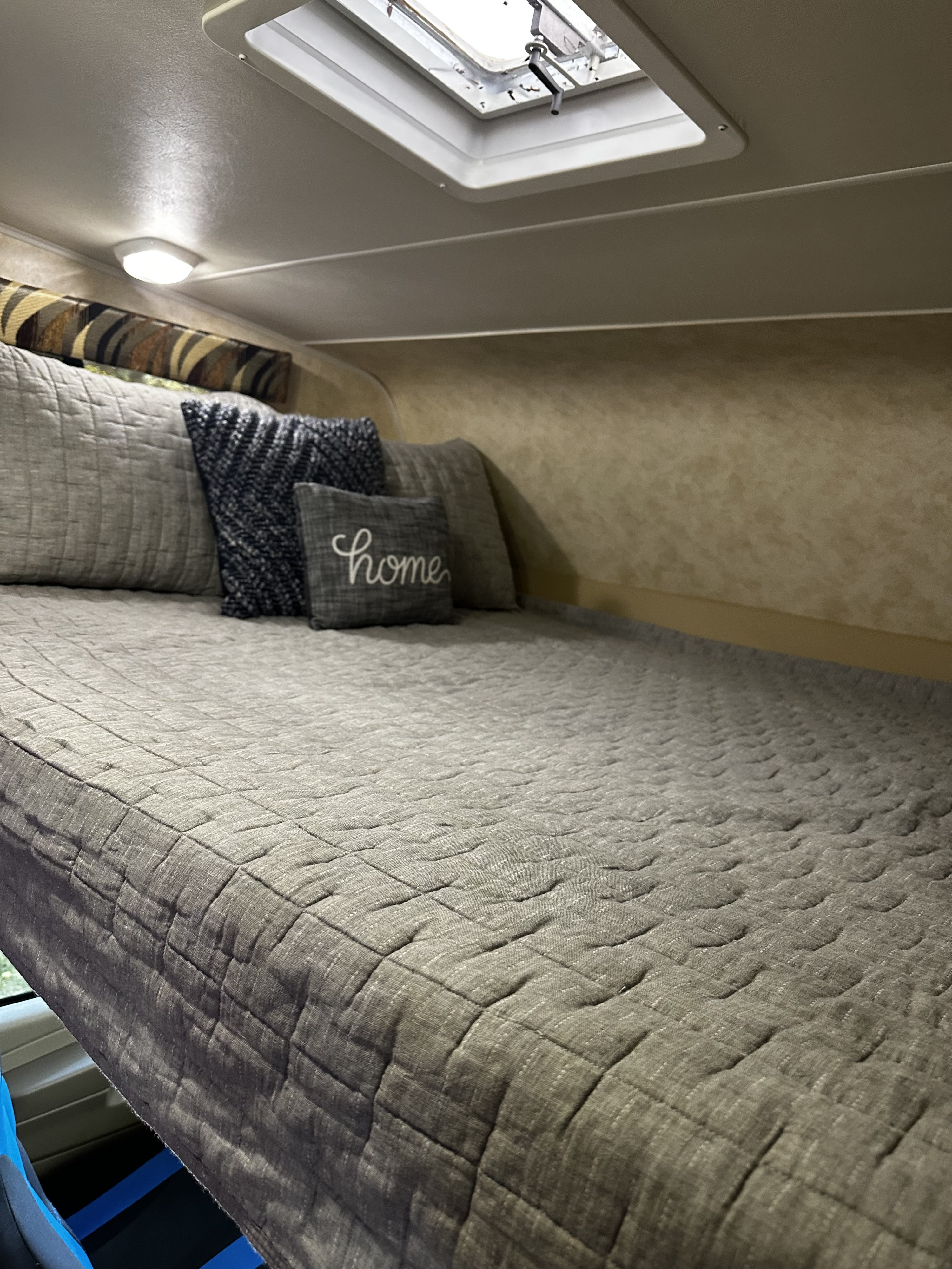 Cozy RV rental bedroom featuring a comfy quilted bed, decorative pillows, and a skylight for natural light.. Coachmen Coachmen Freelander 2013