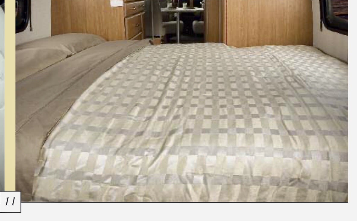 Spacious RV rental bedroom with a checkered bedspread and built-in wooden furniture, ready for your next adventure.. Roadtrek Roadtrek Class B 2010