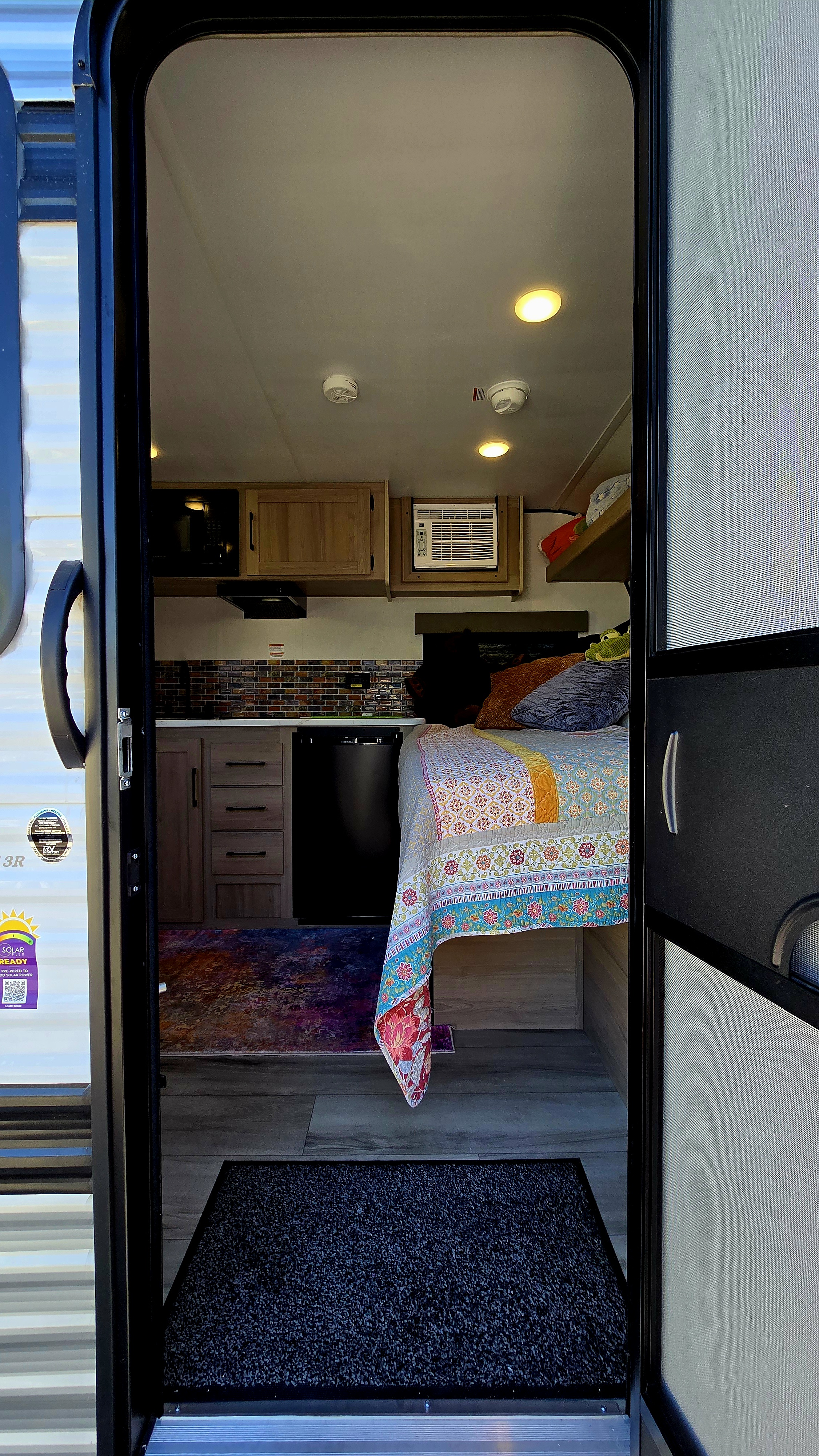 Inside a bright RV rental: compact kitchen, cozy bed, and AC unit. Perfect for comfortable adventures on the road.. Keystone 13r 2026