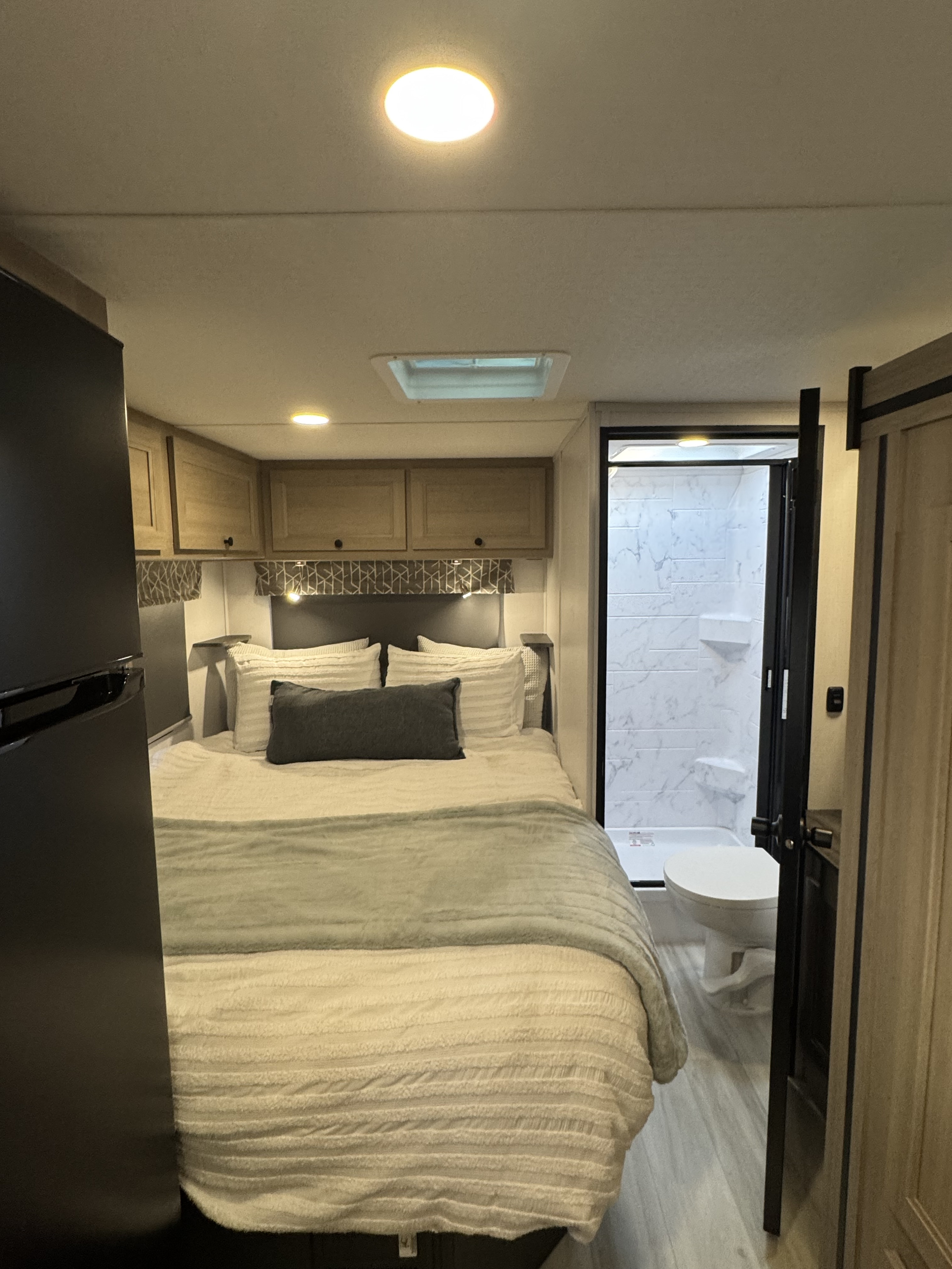 Discover this compact RV rental: a comfortable bedroom with overhead cabinets, an adjacent bathroom/shower, and a prominent fridge.. Forest River Sunseeker 2026