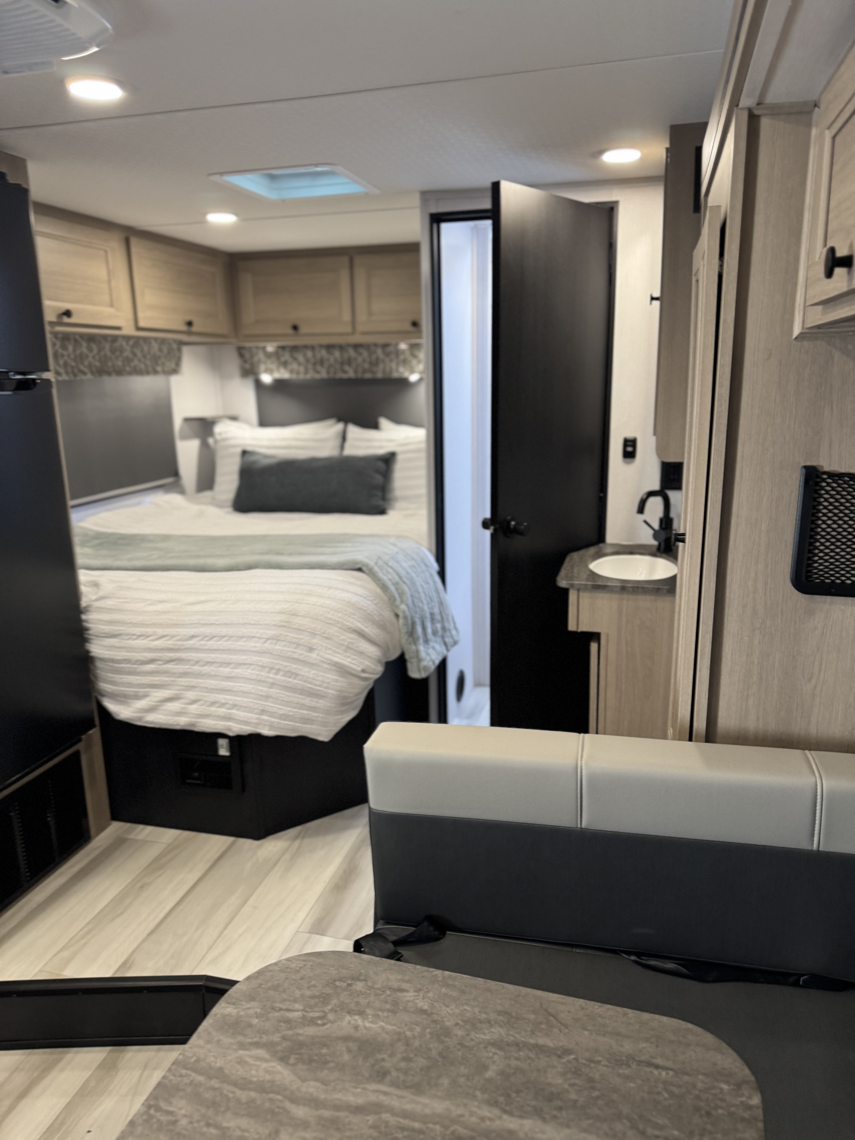 RV rental interior featuring a cozy bedroom, compact bathroom, and dining area. Ideal for comfortable travel adventures.. Forest River Sunseeker 2026