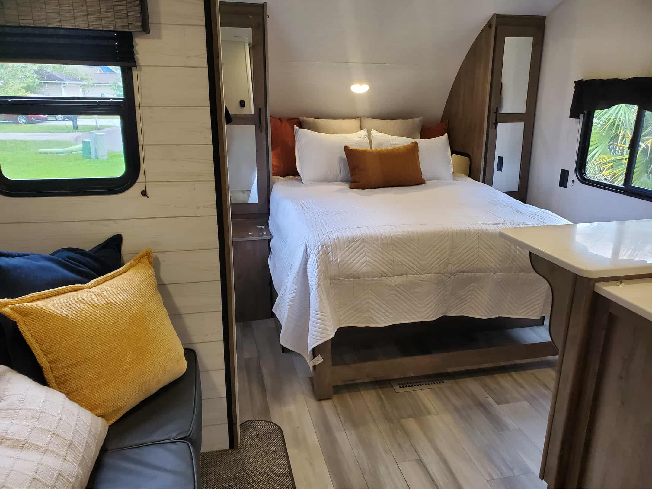 Step into comfort: This RV rental offers a bright bedroom with a queen bed, quilted white bedding, and modern wood accents.. Heartland RVs Pioneer 2023
