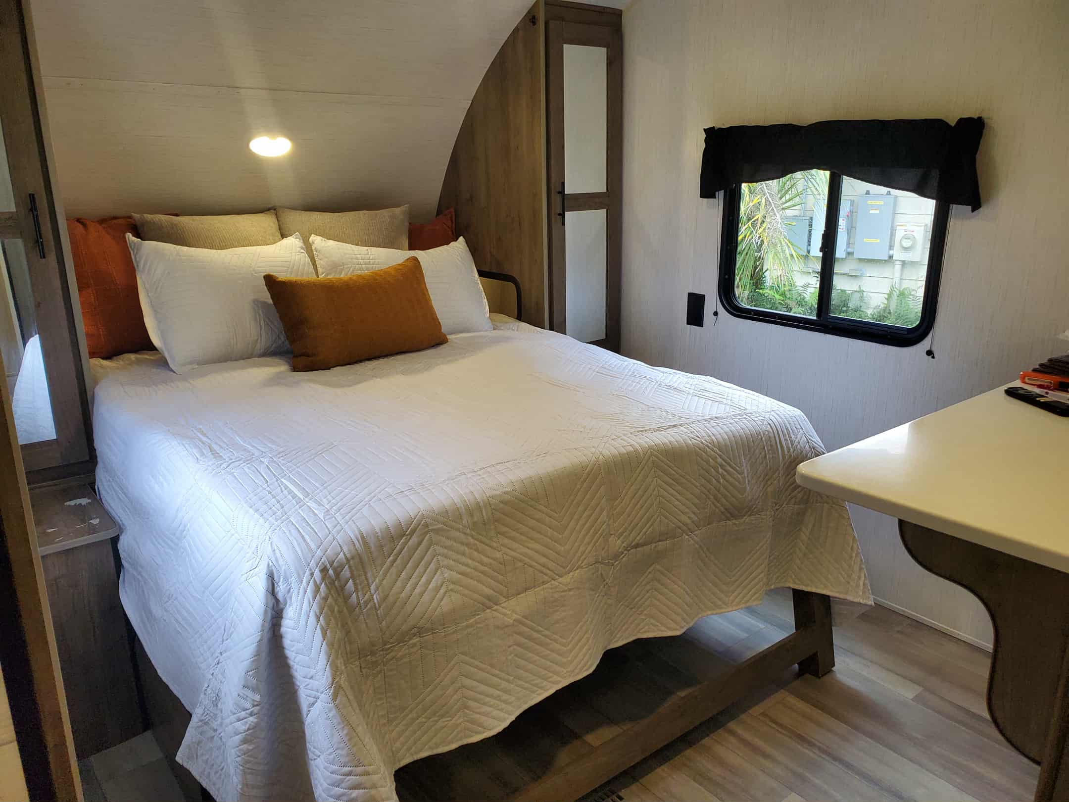 RV rental bedroom: a cozy space featuring a large bed with white quilted bedding, warm pillows, and a window.. Heartland RVs Pioneer 2023
