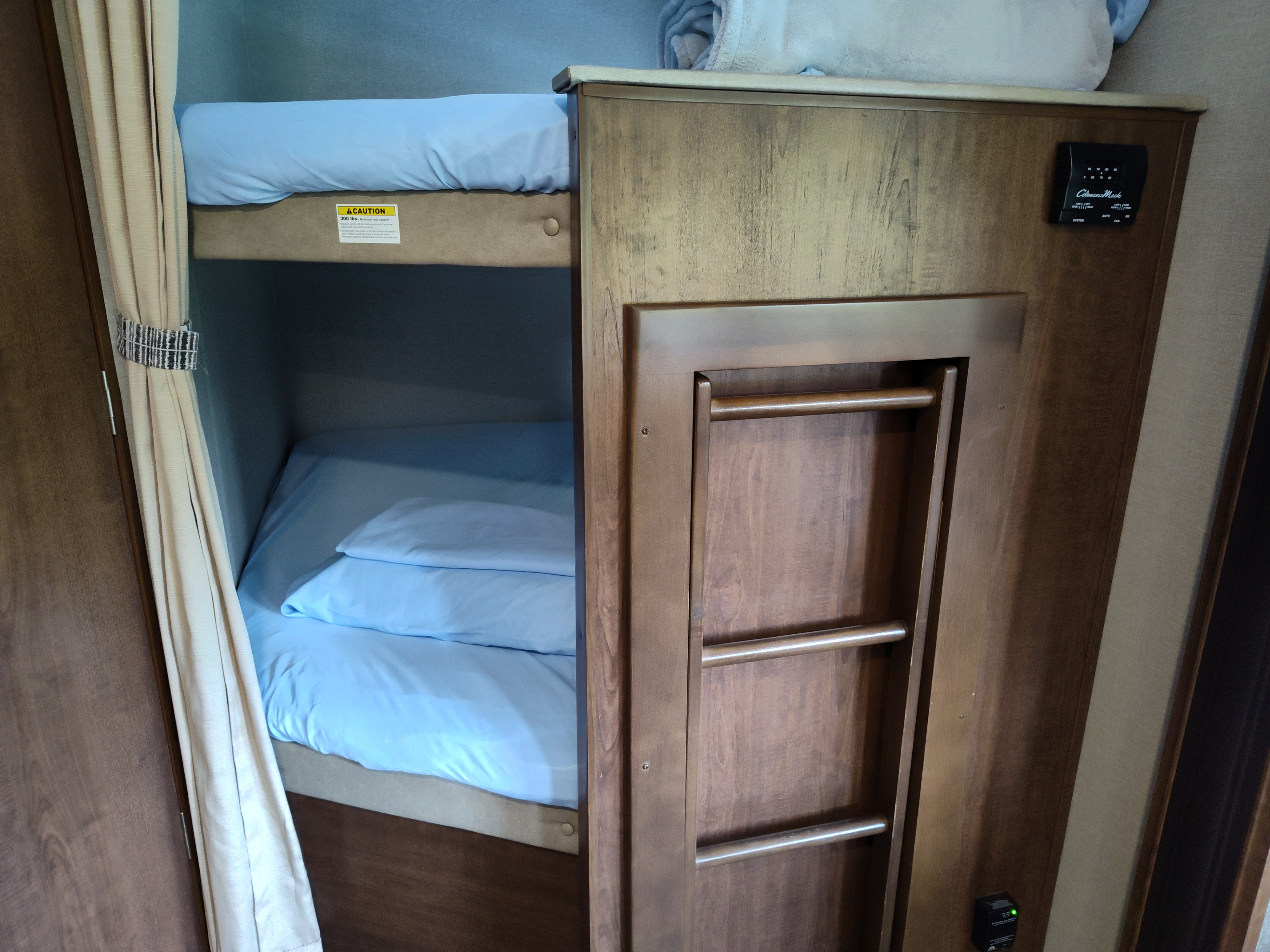 RV rental bunk bed area: two beds with blue bedding, a built-in ladder, and a wall-mounted thermostat.. Keystone Hideout 28BHS 2017