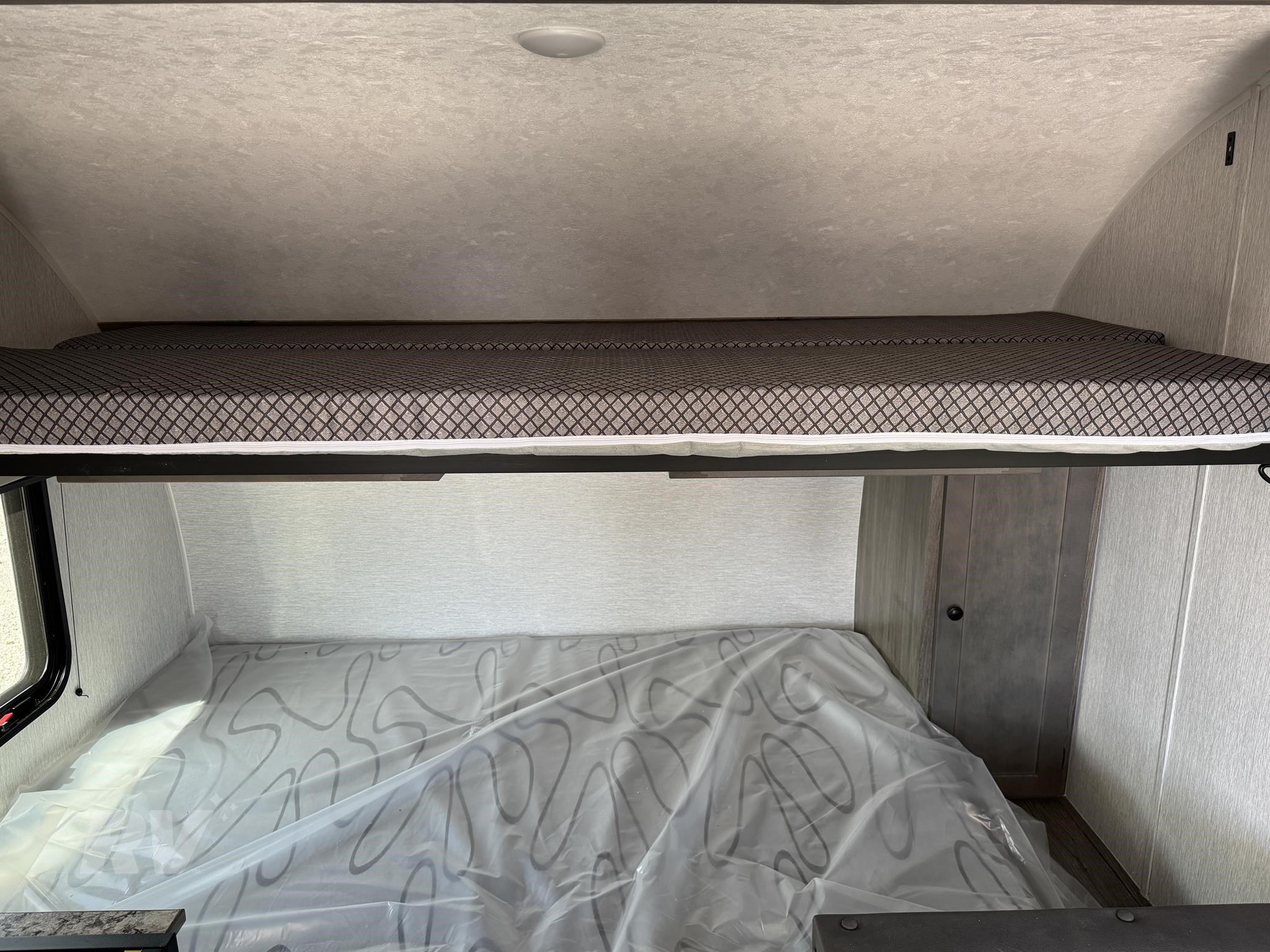 RV rental: Upper bunk bed with patterned mattress, lower bed covered in protective plastic, ready for your adventure.. Sunlite 16BH 2025
