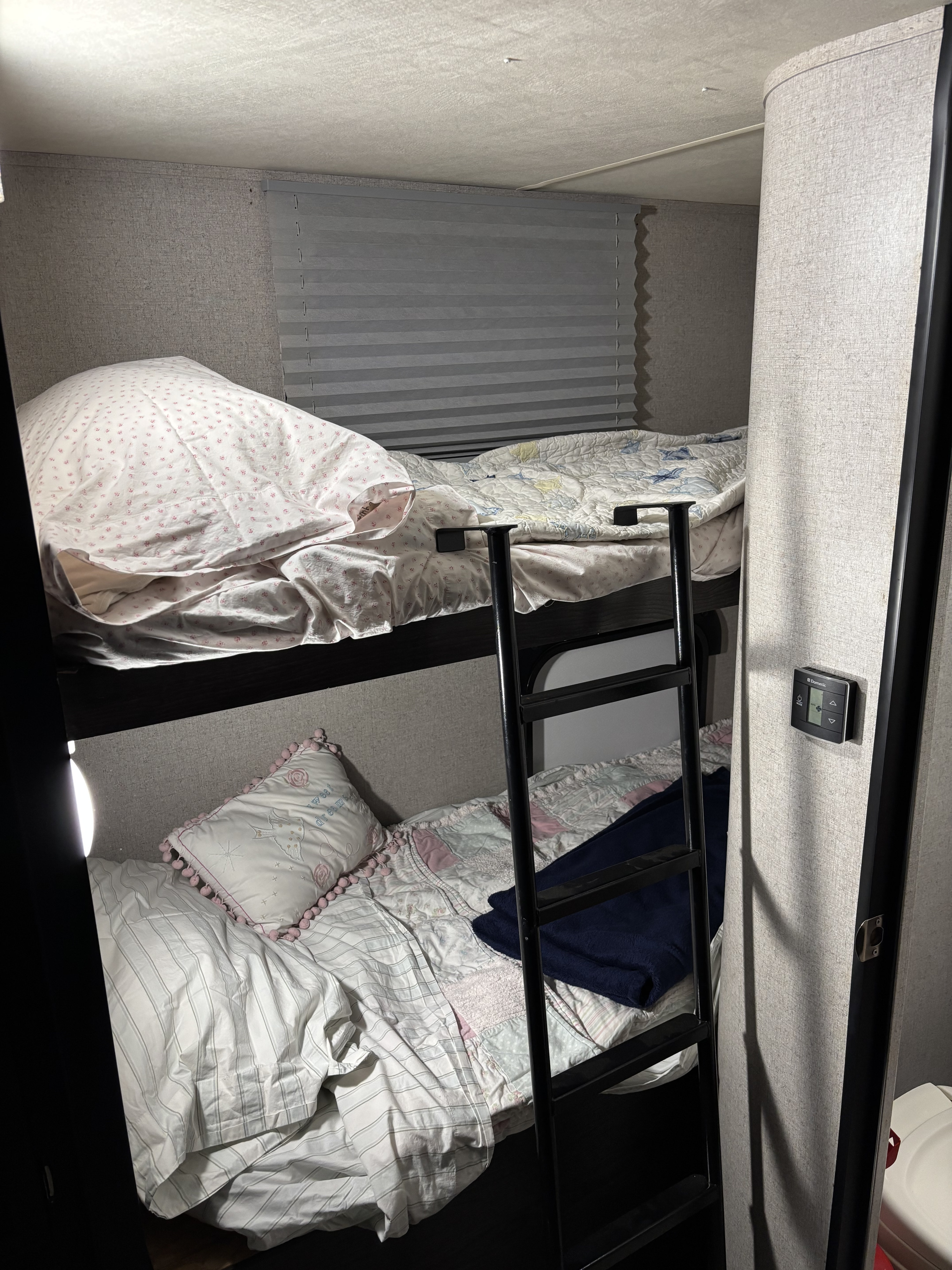 An RV rental's cozy bunk beds, with a ladder & window blinds for a comfortable stay.. Dutchmen Kodiak Express 2018