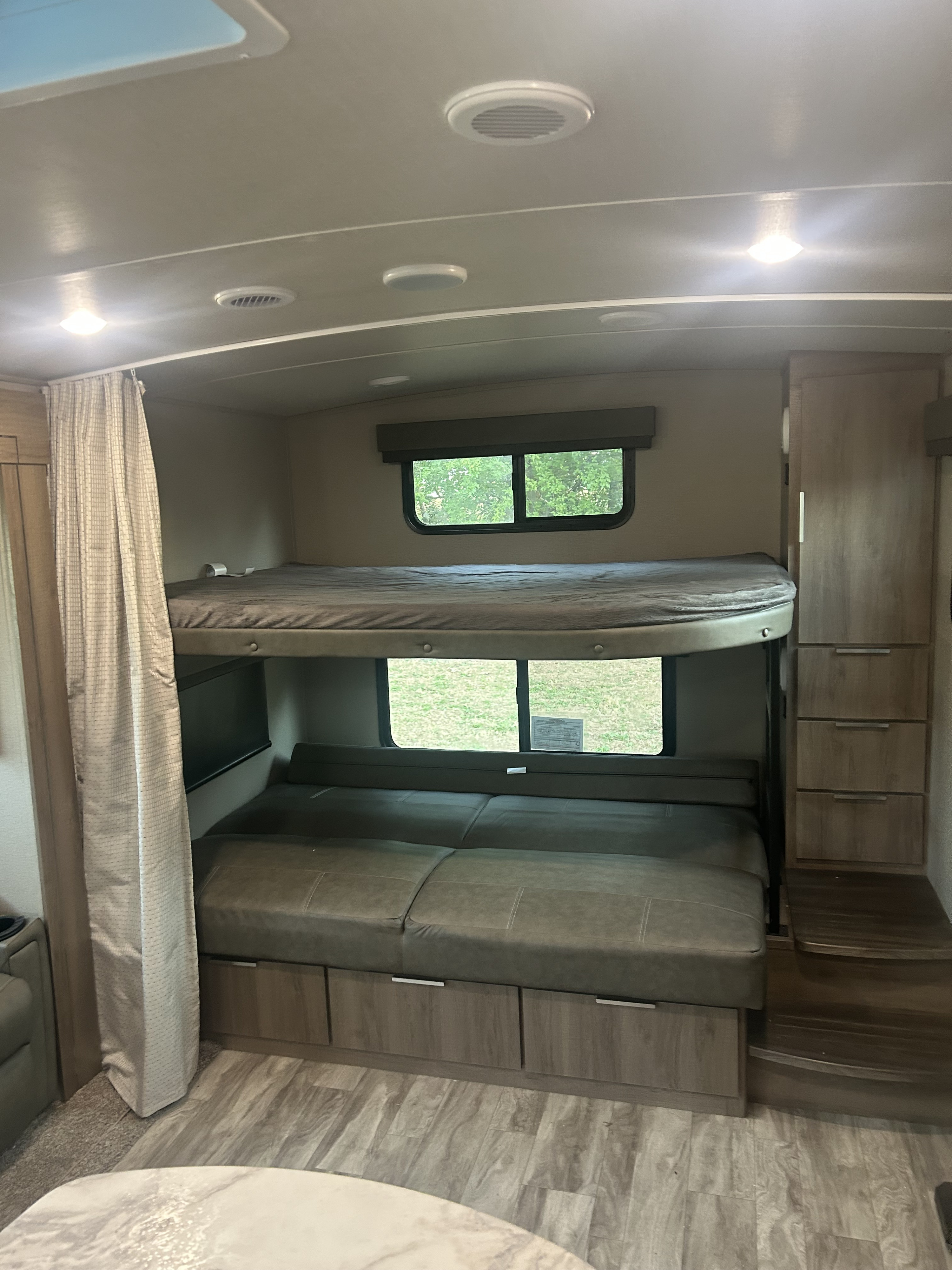 RV rental interior features bunk beds above a convertible dinette/bed with storage cabinets, ideal for family travel.. Grand Design Imagine 2021