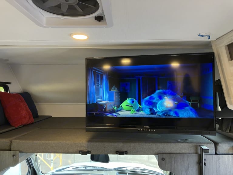 Cozy rv rental: TV showing Monsters, Inc. mounted above a cab-over bunk bed, with a ceiling fan and light overhead.. Forest River Forester 2026