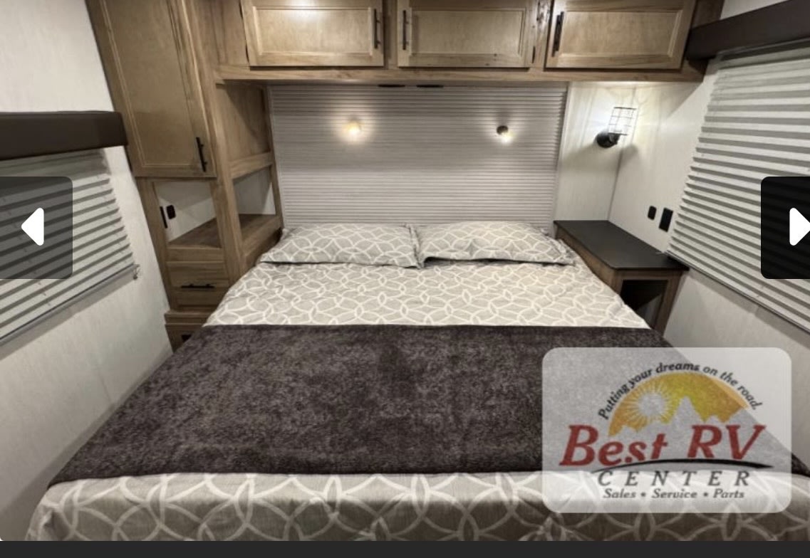 Cozy RV rental bedroom with queen bed, overhead storage, side tables, and dimmable sconces for relaxing travel.. Forestriver Timberwolf 20OG 2025