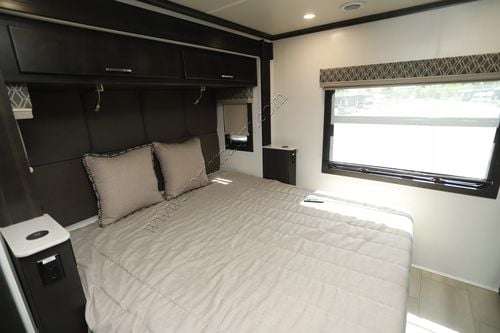 Comfortable RV rental bedroom: light bed, dark headboard, overhead storage, and a large window. Ideal for road trips!. DX3 DX3 Motorhome 2022
