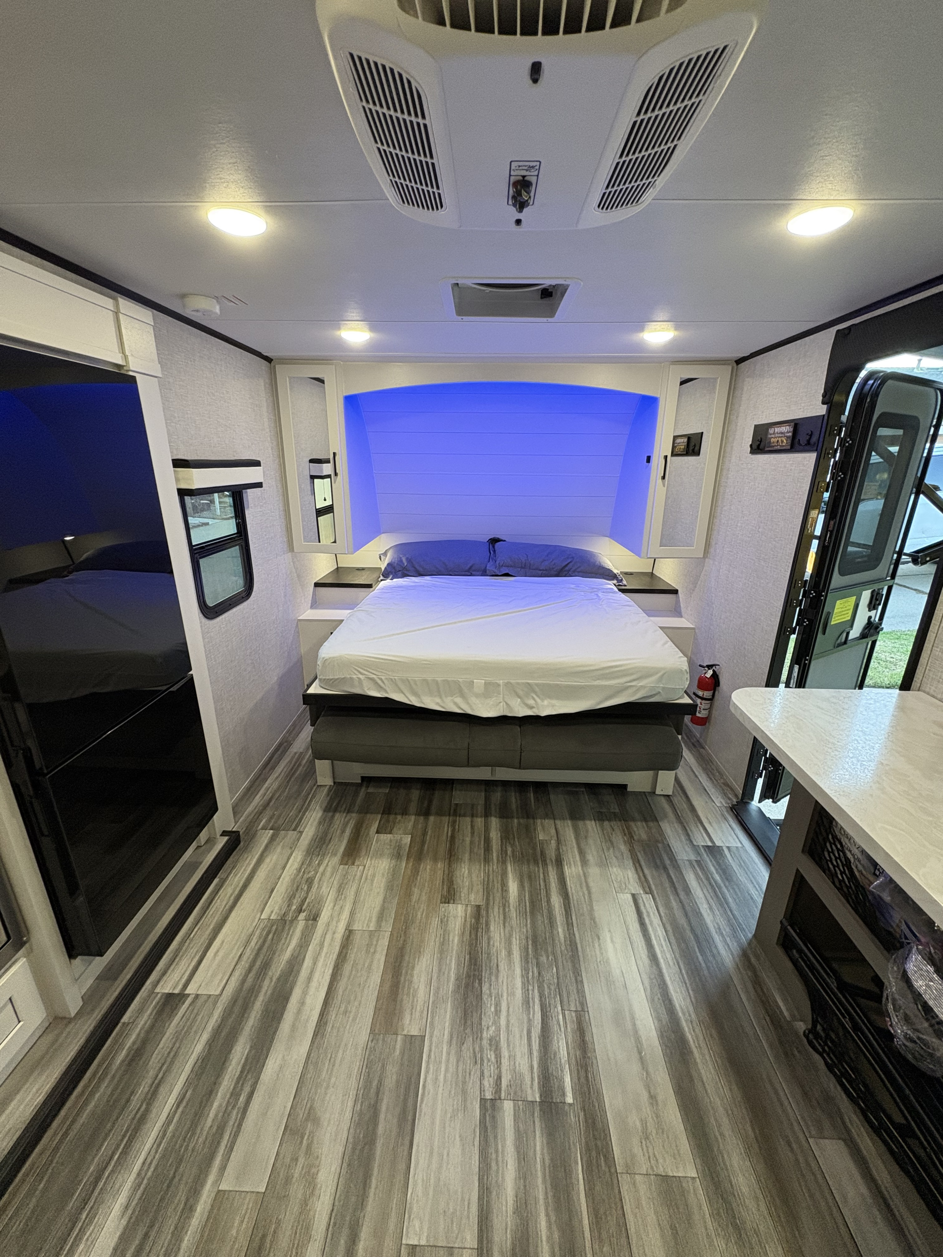 Modern RV rental interior with a cozy bedroom featuring blue accent lighting and wood-look flooring.. Jayco Jay Feather 18MBH 2025