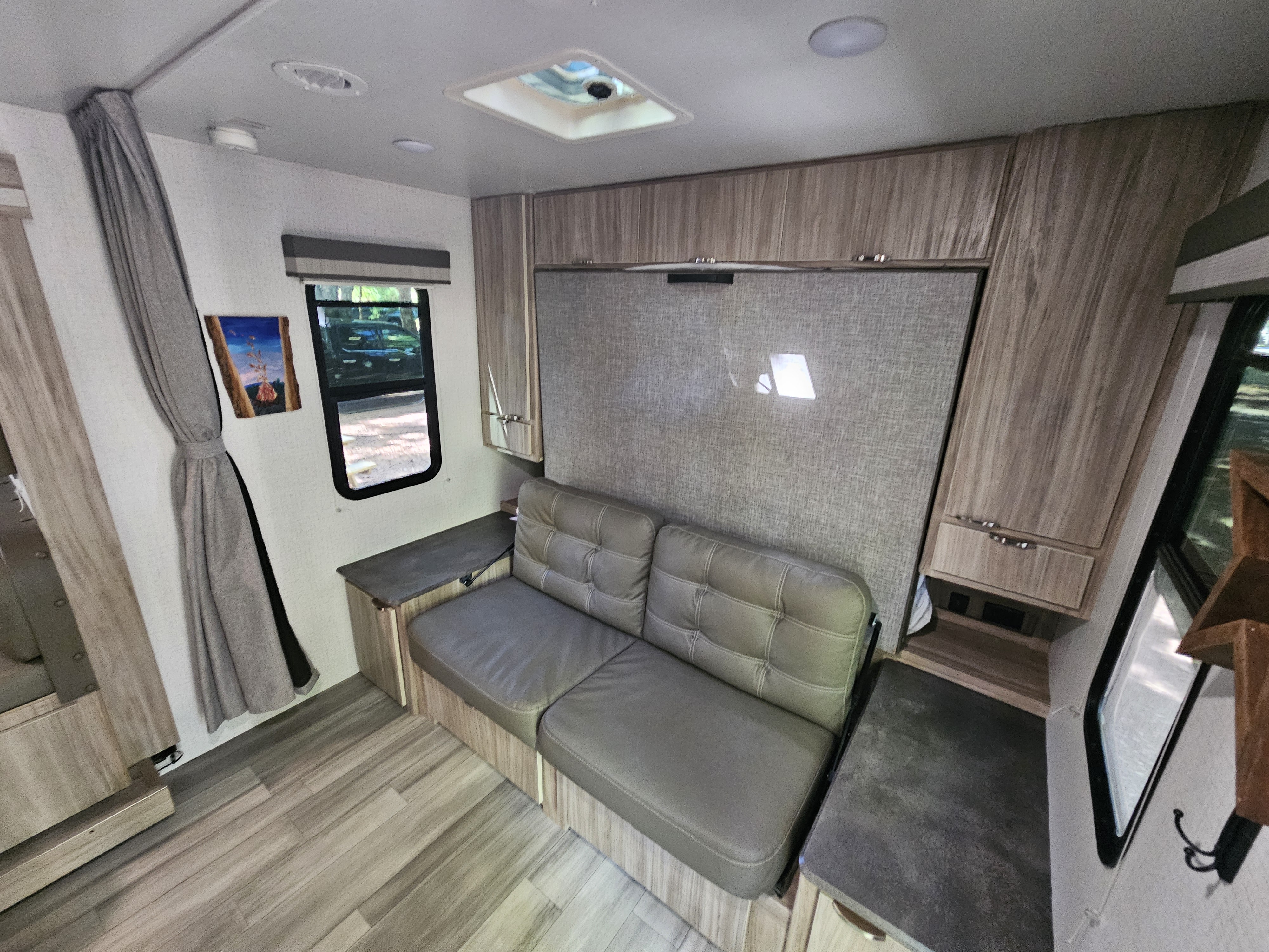 Inside this RV rental: A compact yet comfortable camper living area featuring a sofa, wall bed, and storage cabinets.. Winnebago Minnie 2201MB 2022