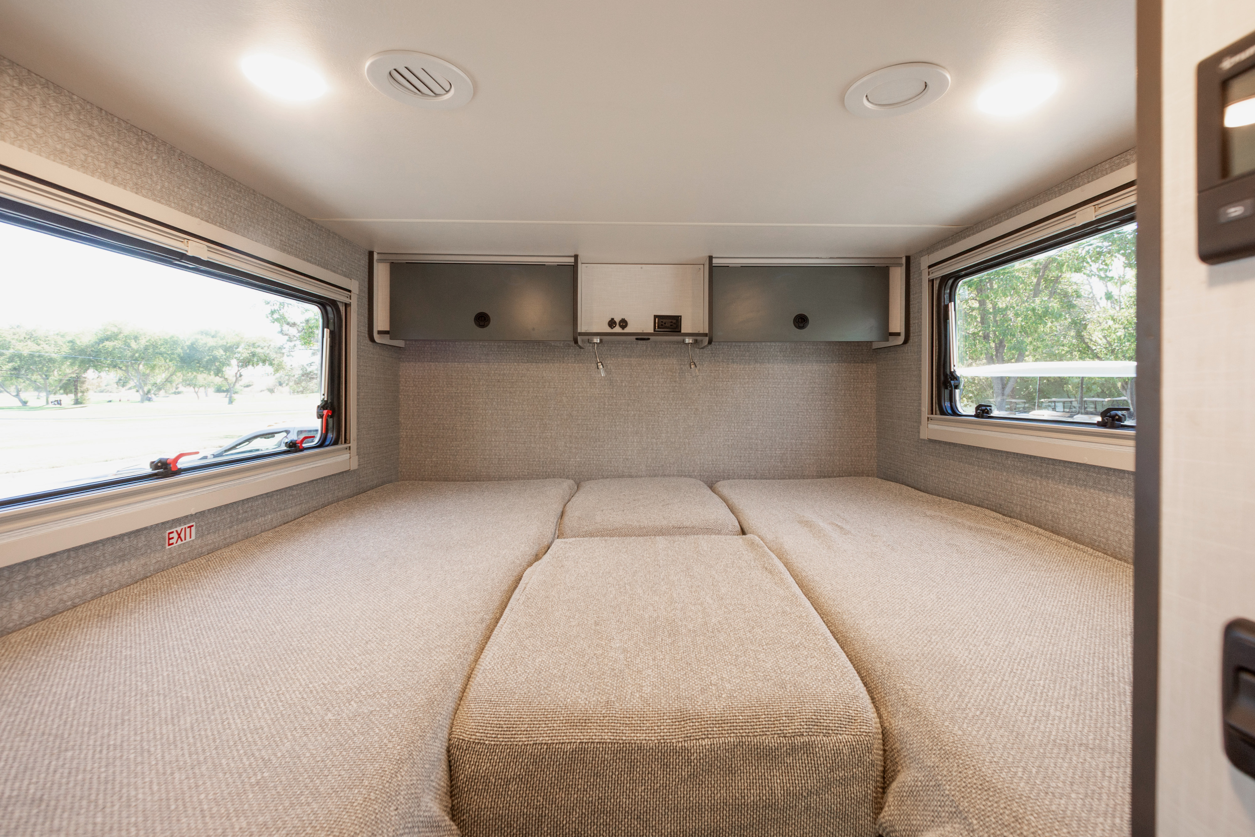 RV rental interior shows a segmented bed, ample storage, and large windows with a green outdoor view for comfortable travel.. Winnebago EKKO 23B AWD 2026