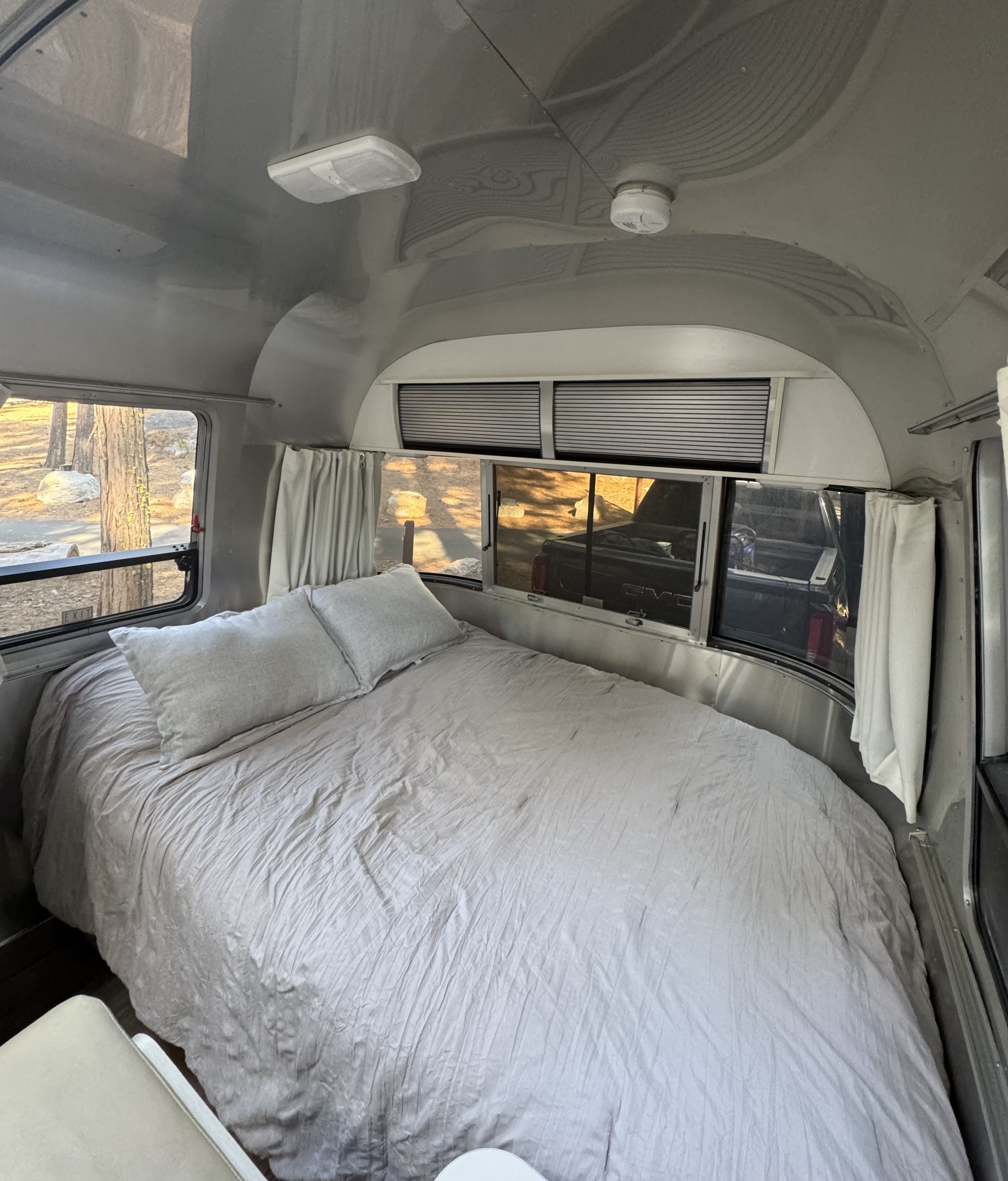 Airstream RV rental bedroom with soft grey bedding and nature views outside. Ideal for travel and relaxation.. Airstream Sport 2018