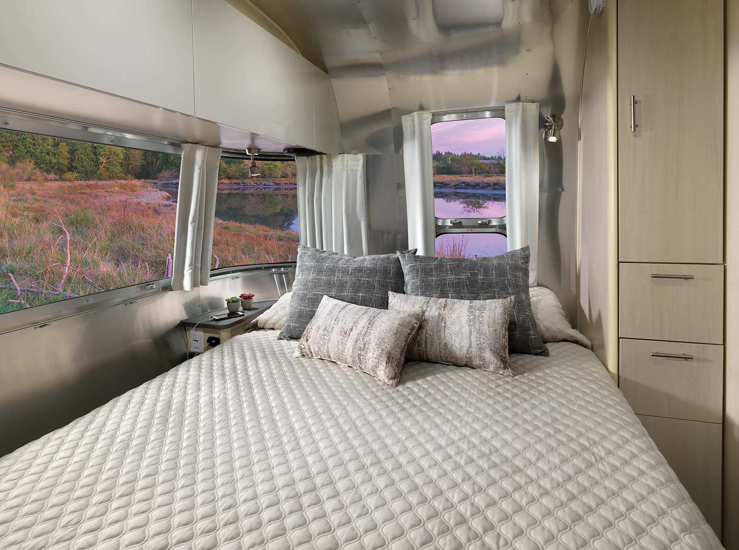 Comfortable Airstream RV rental bedroom with a scenic riverside view, featuring a large bed and cozy decor.. Airstream Flying Cloud 2023
