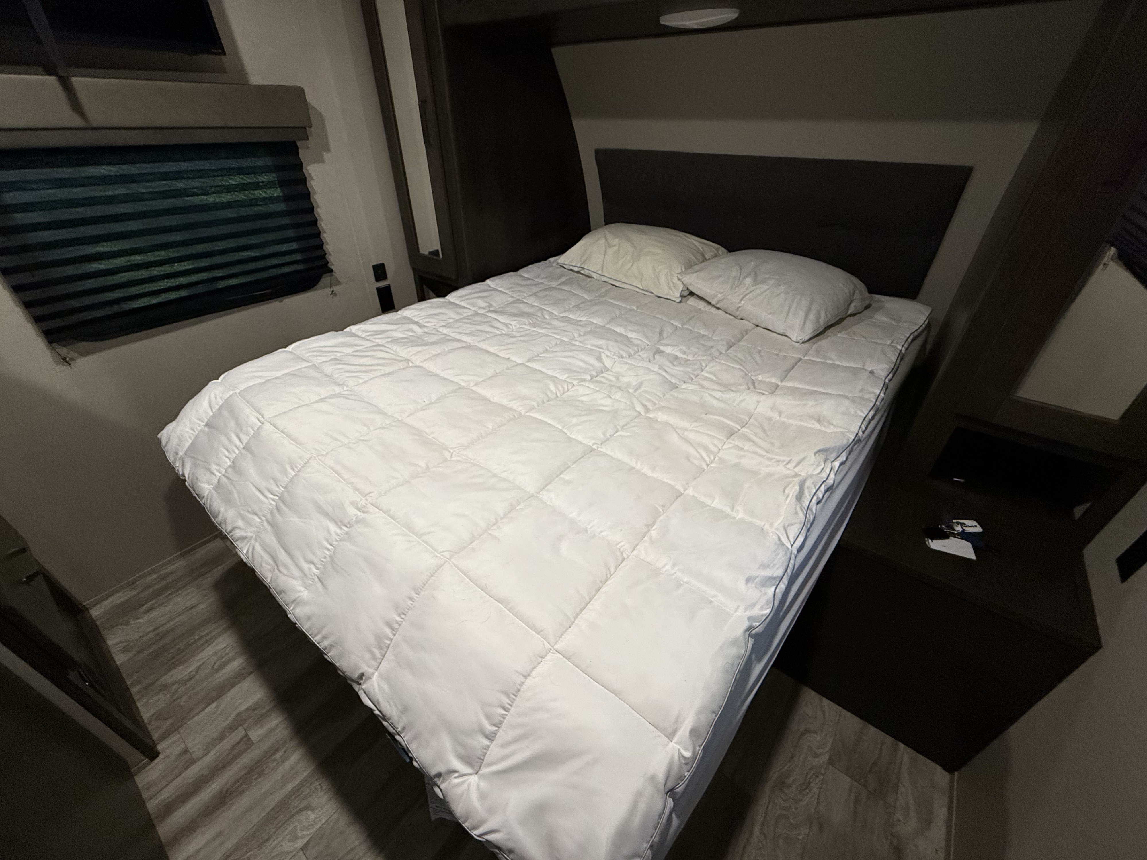 Cozy RV rental bedroom featuring a neatly made bed with a white comforter, pillows, and window blinds.. Grand Design Transcend Xplor 2022