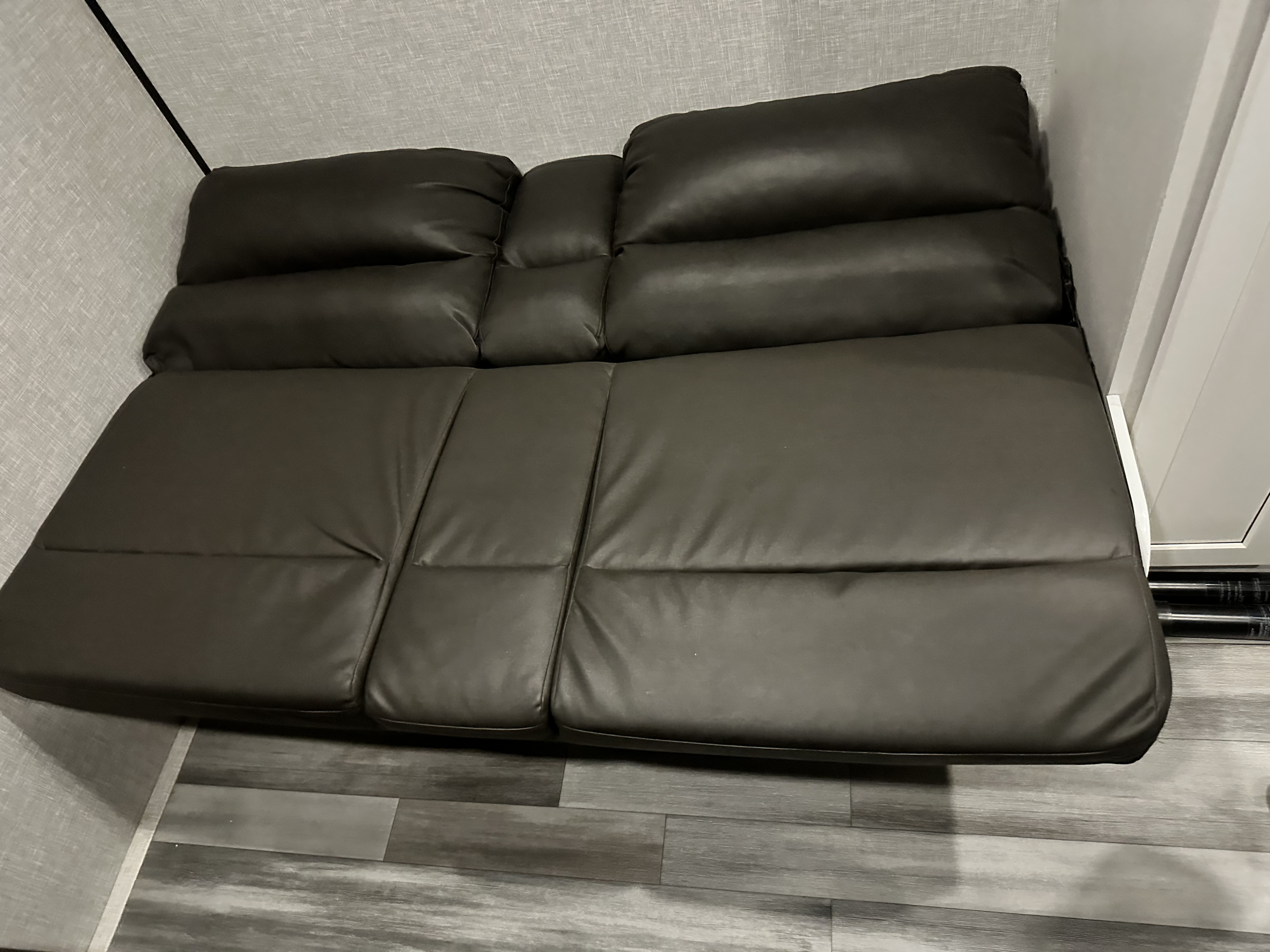Dark gray convertible sofa in an RV rental, offering comfortable seating or an extra bed, set against light walls and wood-look flooring.. Jayco Jay Flight SLX 2024