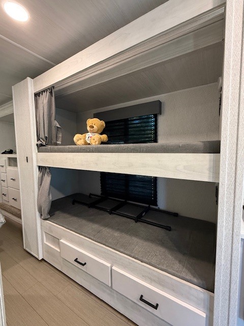 Cozy RV rental bunk beds with a teddy bear, featuring storage drawers. Perfect for family adventures and sleeping areas.. Forest River East to West Entrada 2024