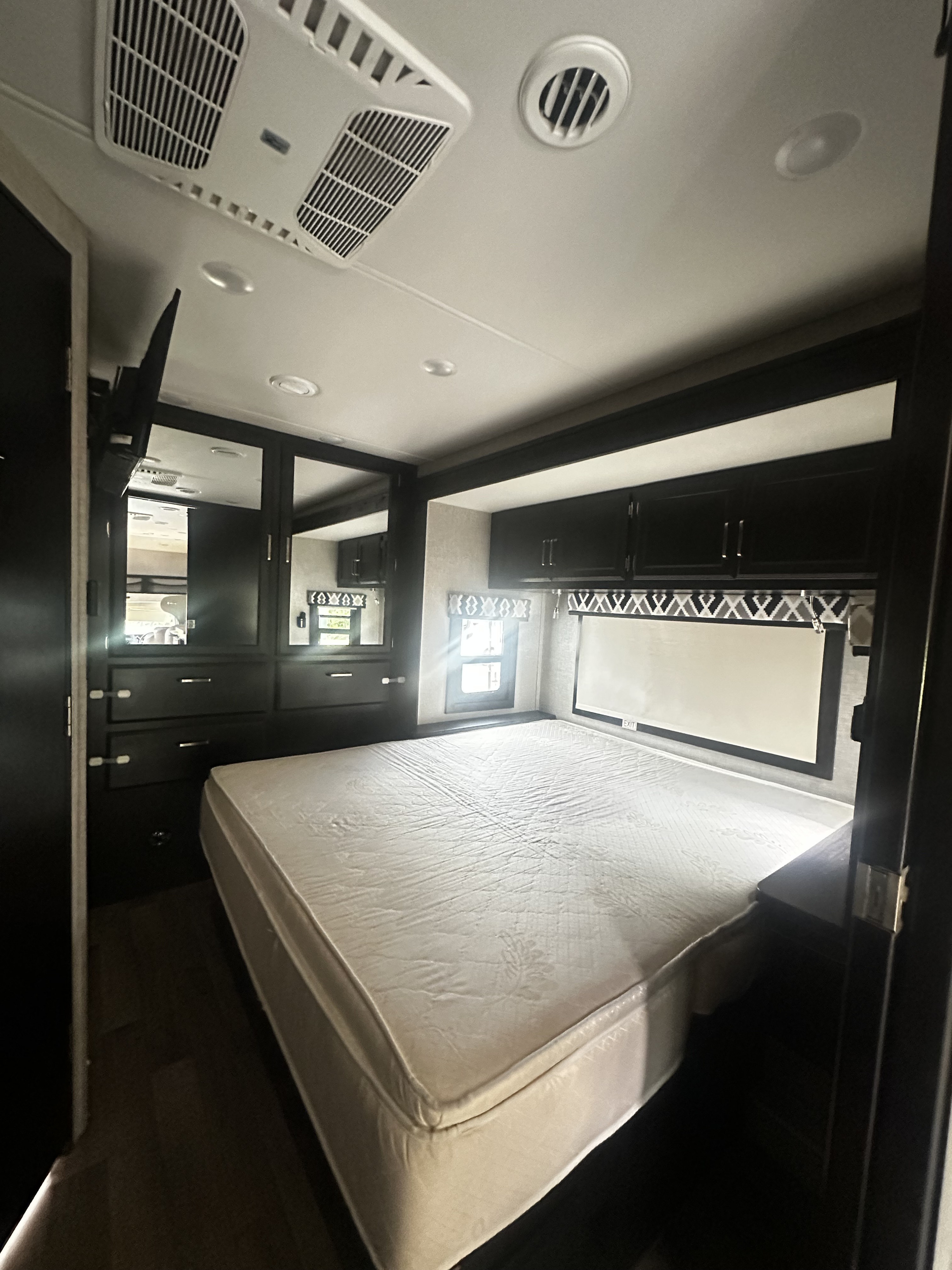 Spacious RV rental bedroom with a large mattress, built-in dark storage, and overhead AC unit for comfortable travel.. Jayco Greyhawk 2022