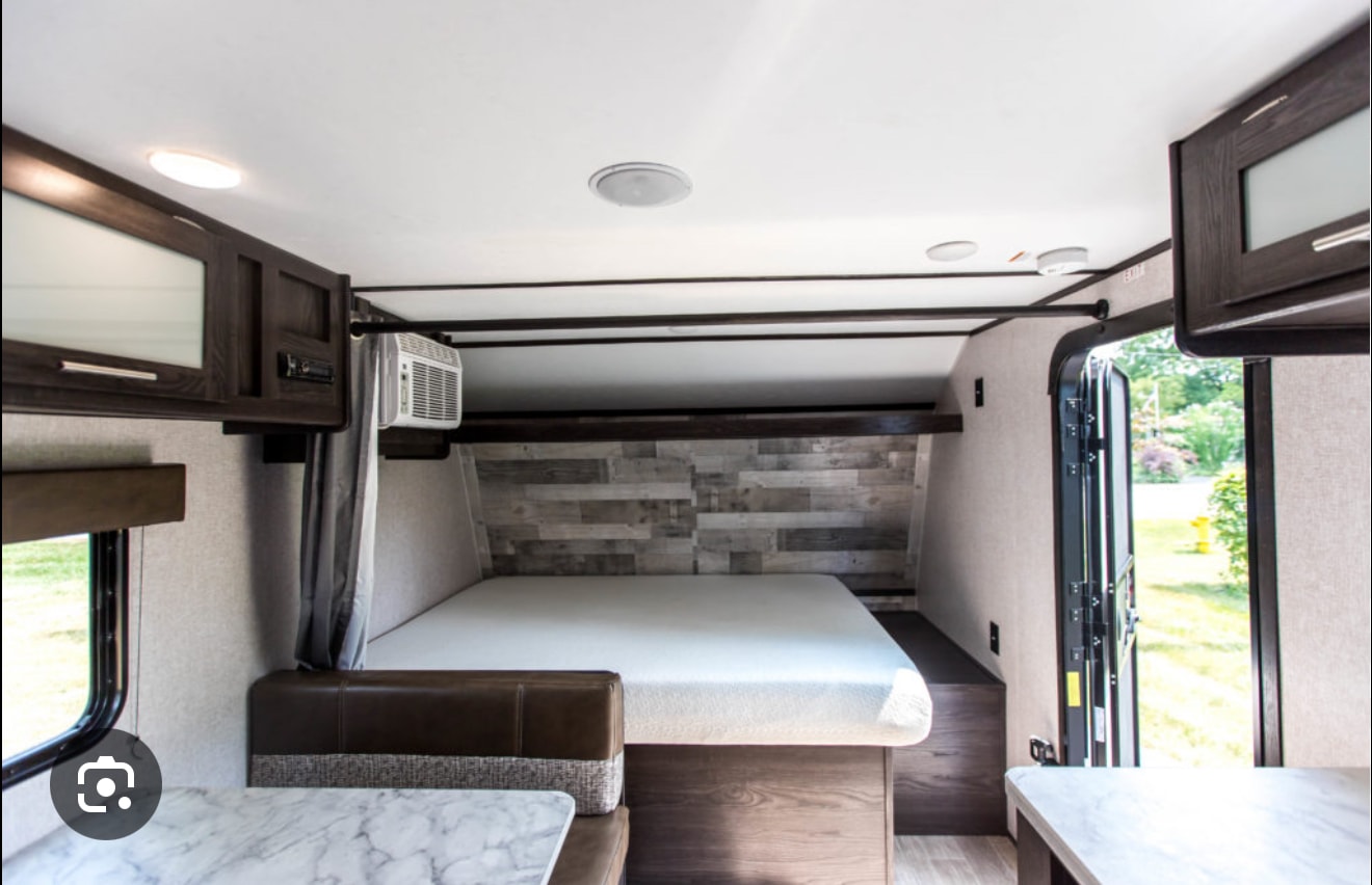 RV rental interior features a comfortable bed, dinette, and sleek overhead cabinets, ideal for your next road trip adventure.. Coleman 17B Lantern 2021