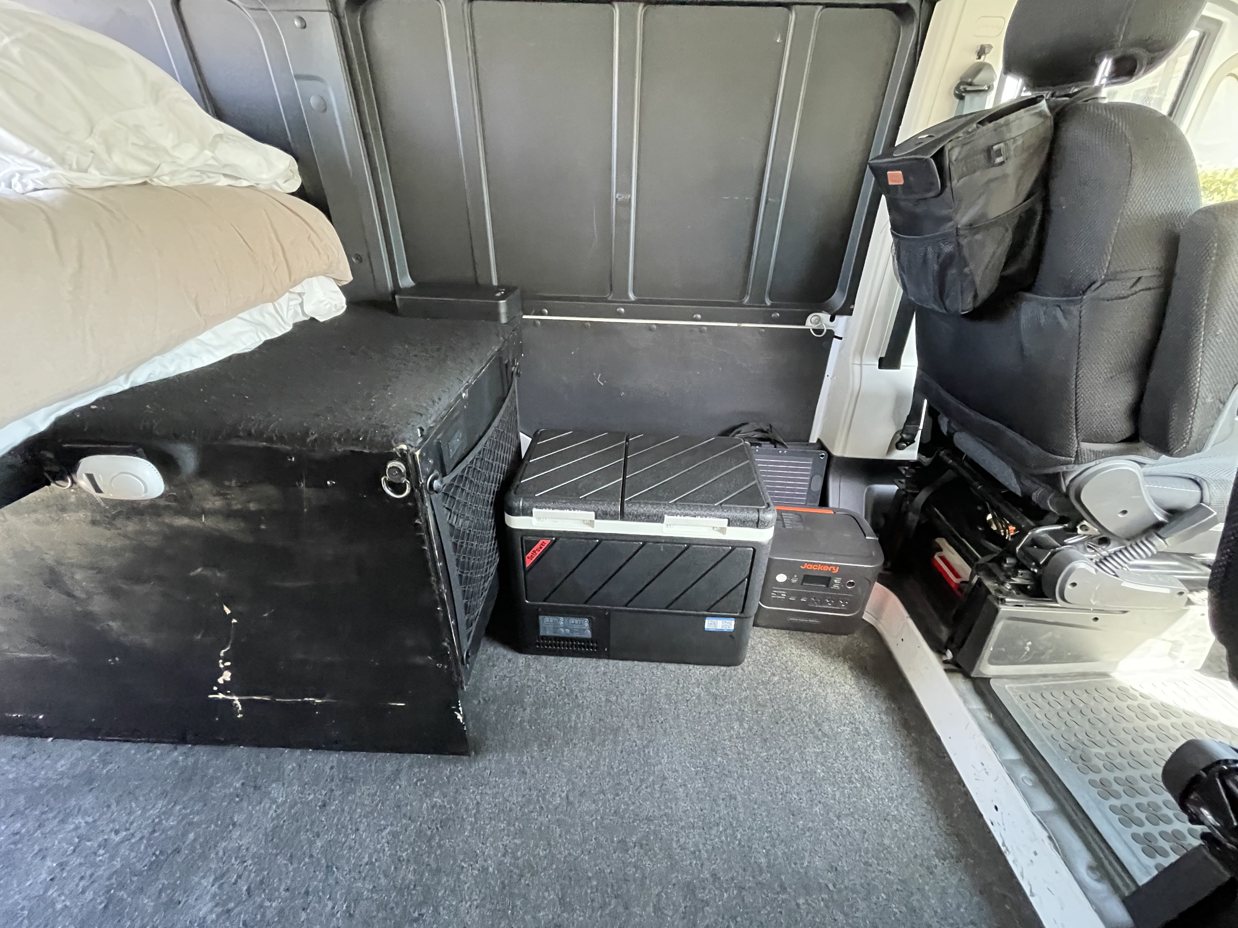 This RV rental interior offers a bed, portable fridge, Jackery power, and seat storage for comfortable travel.. Ram Promaster 2022