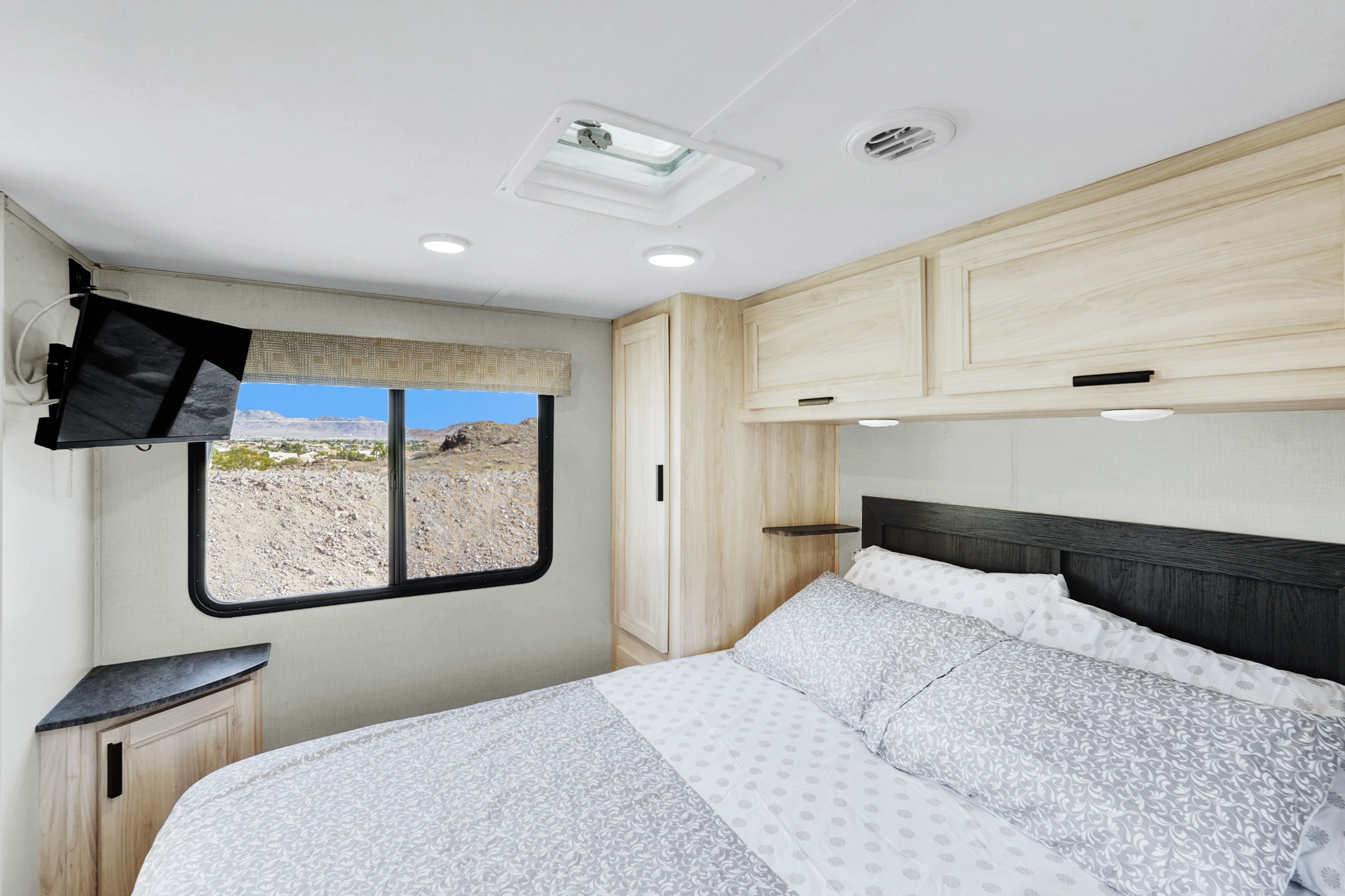 Cozy RV rental bedroom with a comfortable bed, overhead cabinets, and a scenic desert view, perfect for travel.. Forest River Sunseeker LE 2023