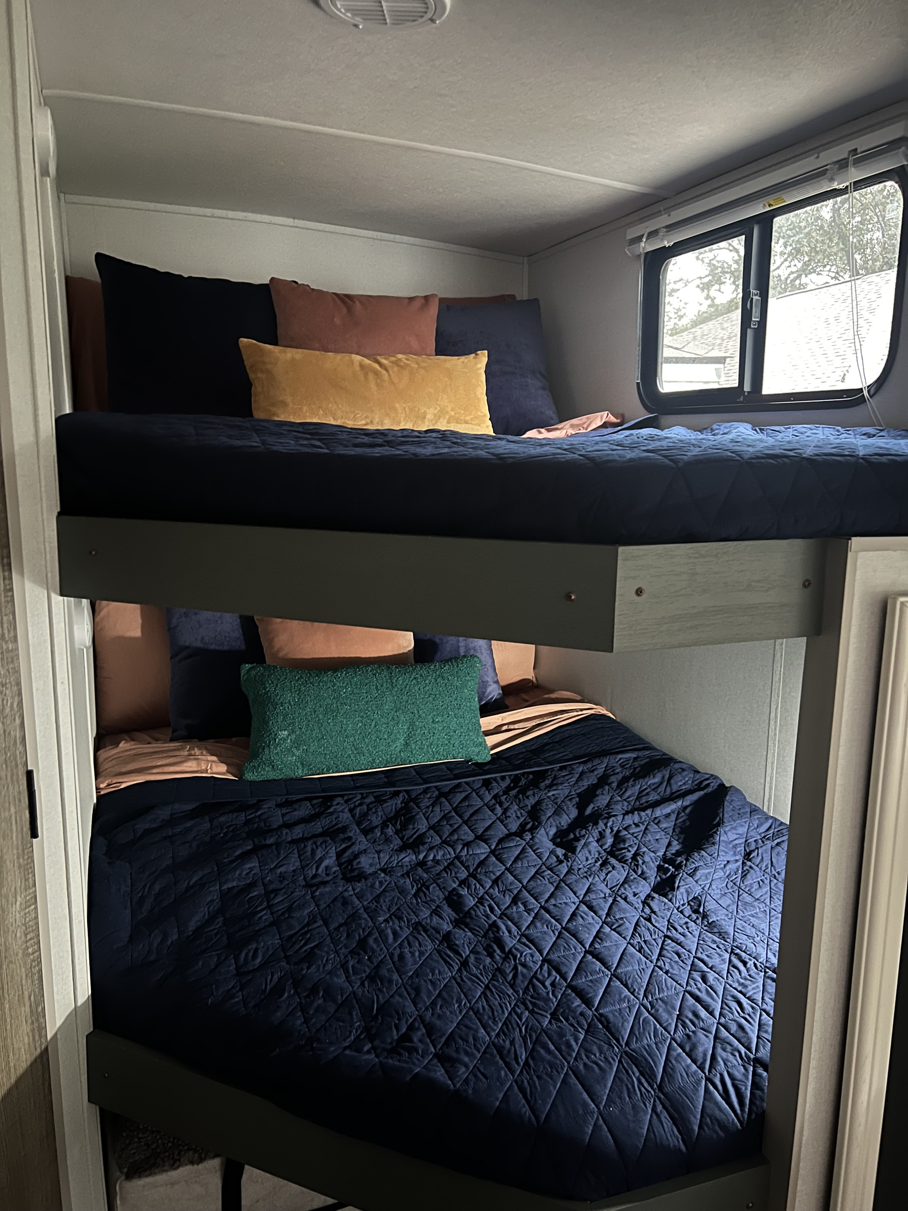 Cozy RV rental bunk beds with navy bedding and colorful pillows. A comfortable sleeping area for your next adventure.. Heartland RVs 265BH-L 2024
