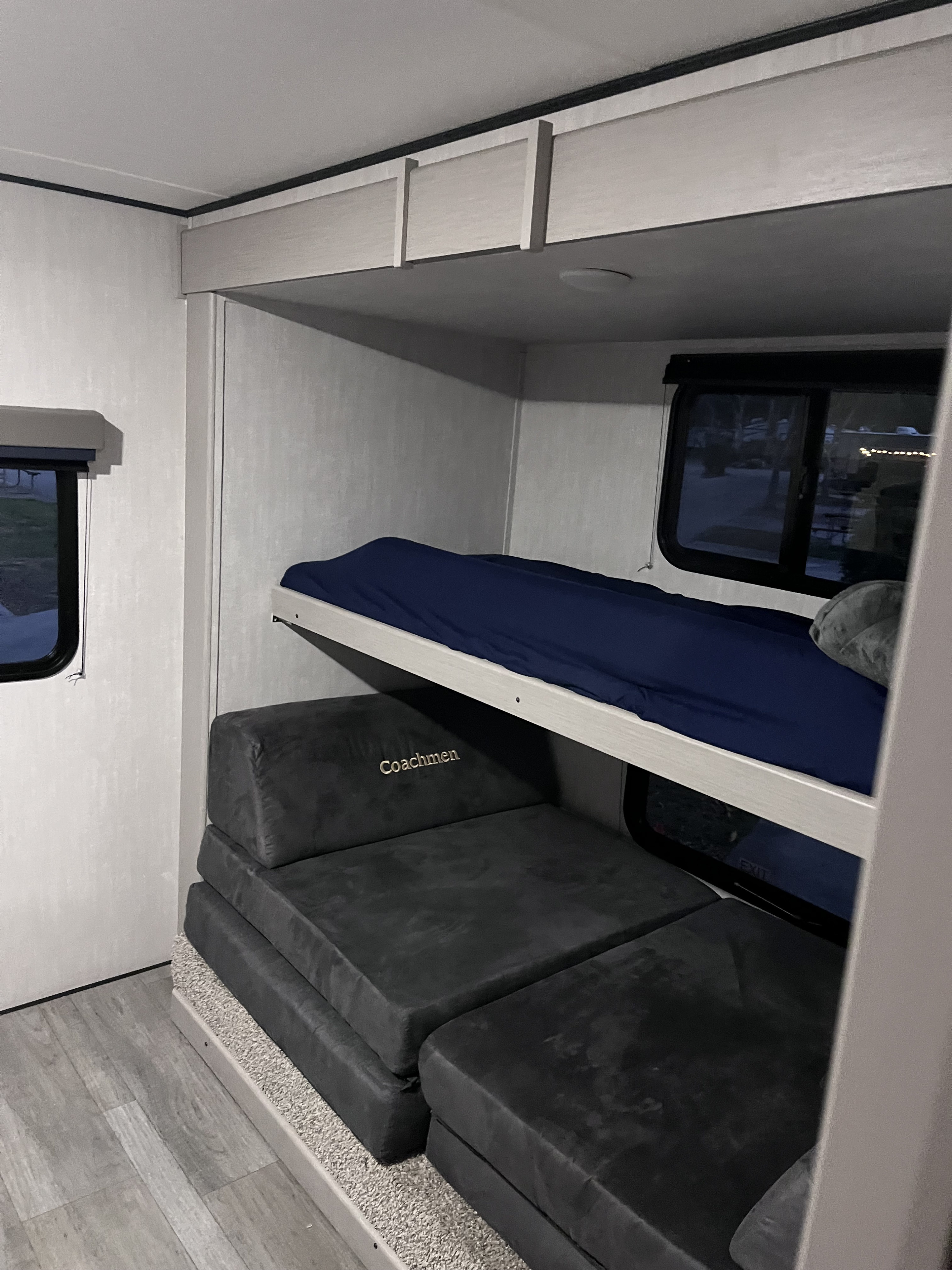 RV rental interior: bunk beds with blue bedding, 'Coachmen' modular seating, and windows. Comfortable sleeping/living space.. Coachmen Apex 300 BHS 2025