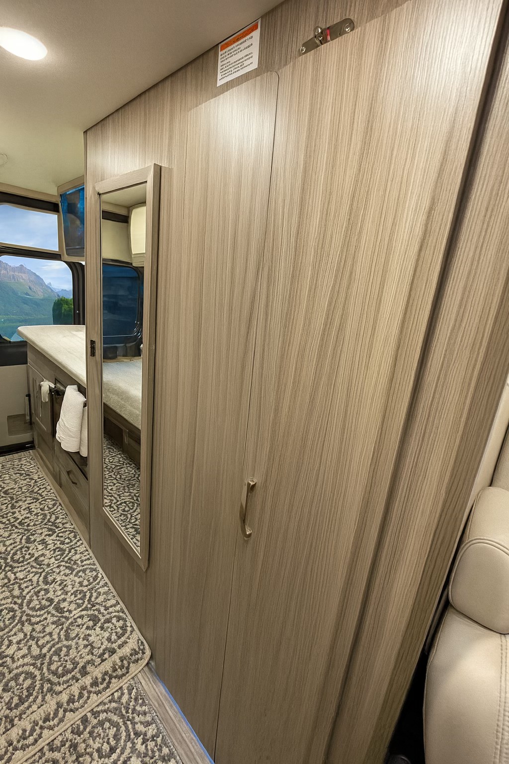 Compact RV rental interior featuring a stylish wardrobe with integrated mirror, counter space, and a scenic window view.. Jayco Swift 2023