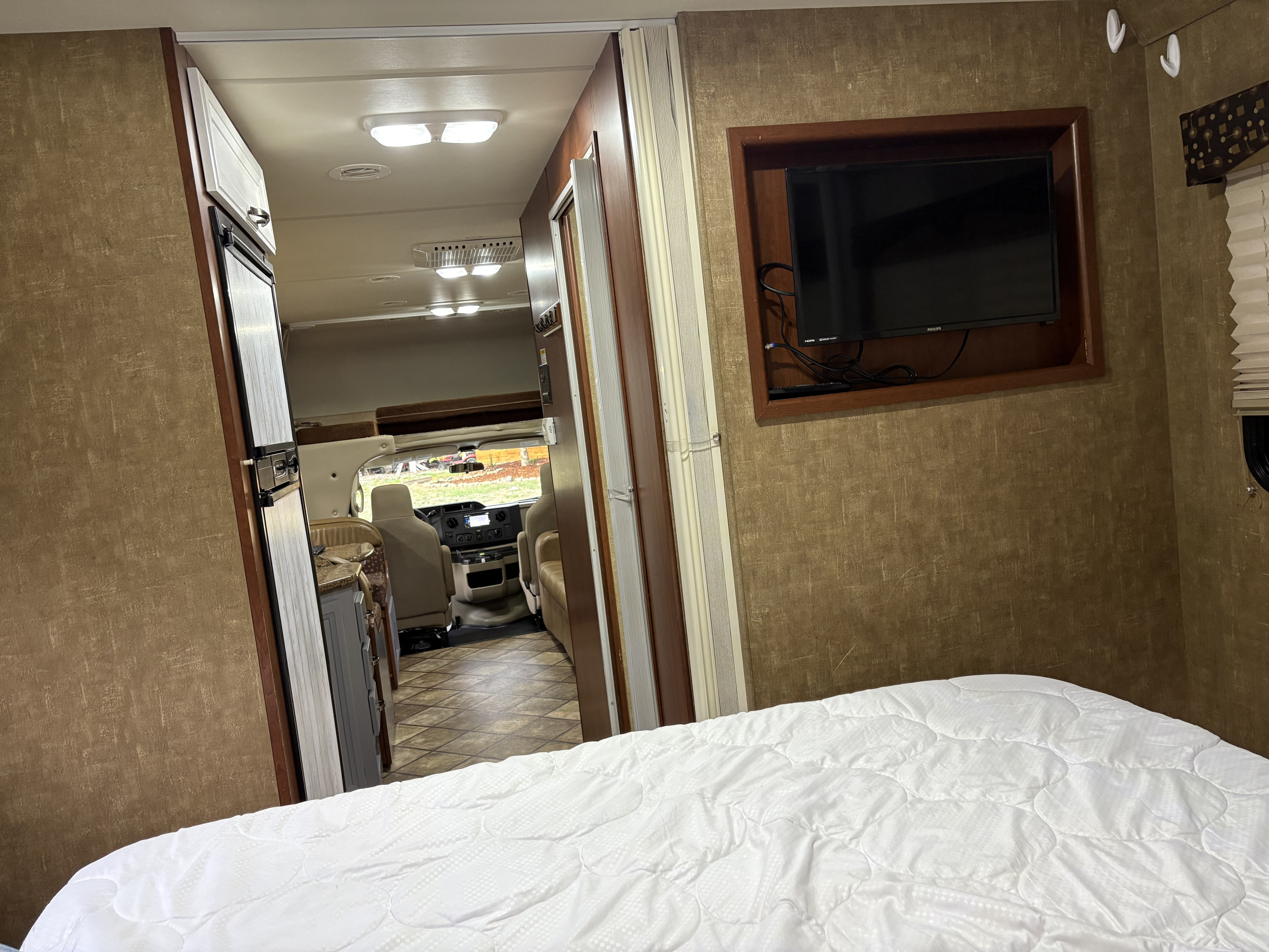 Peek inside this inviting rv rental. Features a comfortable bed, TV, and a glimpse of the front cabin area.. Thor Freedom Elite 2014