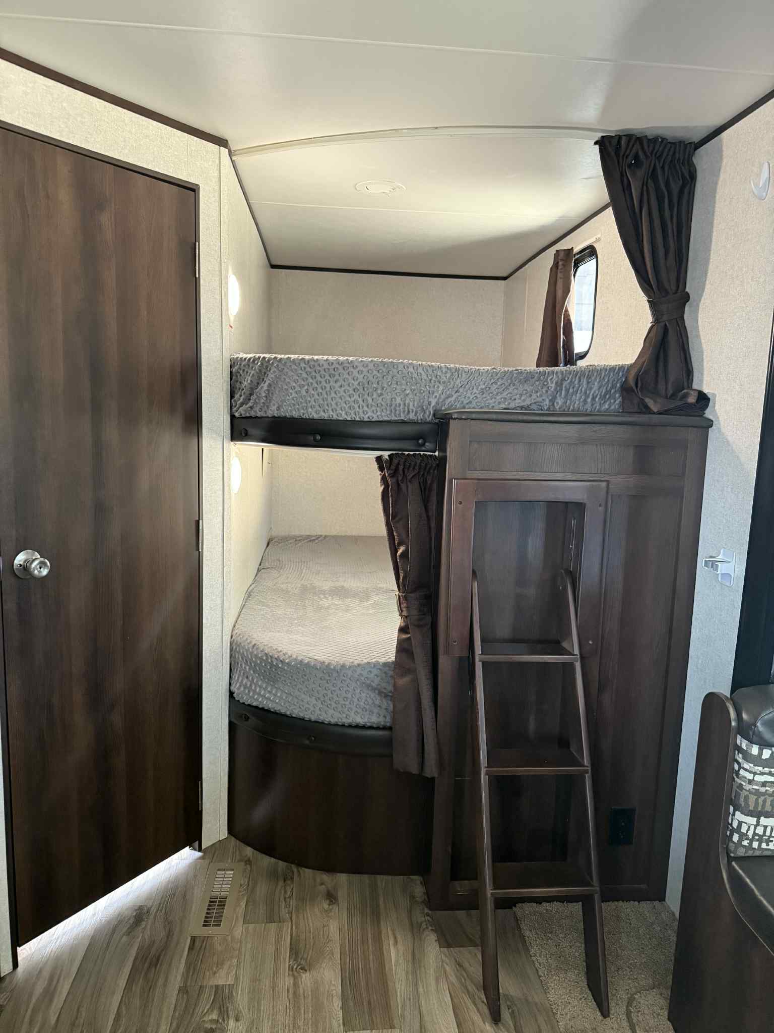 Inside this RV rental, comfortable dark wood bunk beds with gray bedding, privacy curtains, and a ladder for access.. Jayco Jay Flight SLX Rocky Mountain Edition 2018