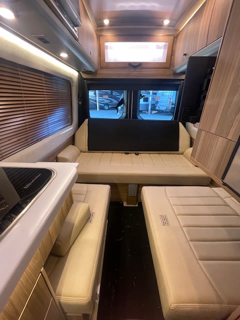 Spacious RV rental interior featuring a large convertible bed, side benches, and kitchen counter for comfortable travel.. Airstream Interstate 2023