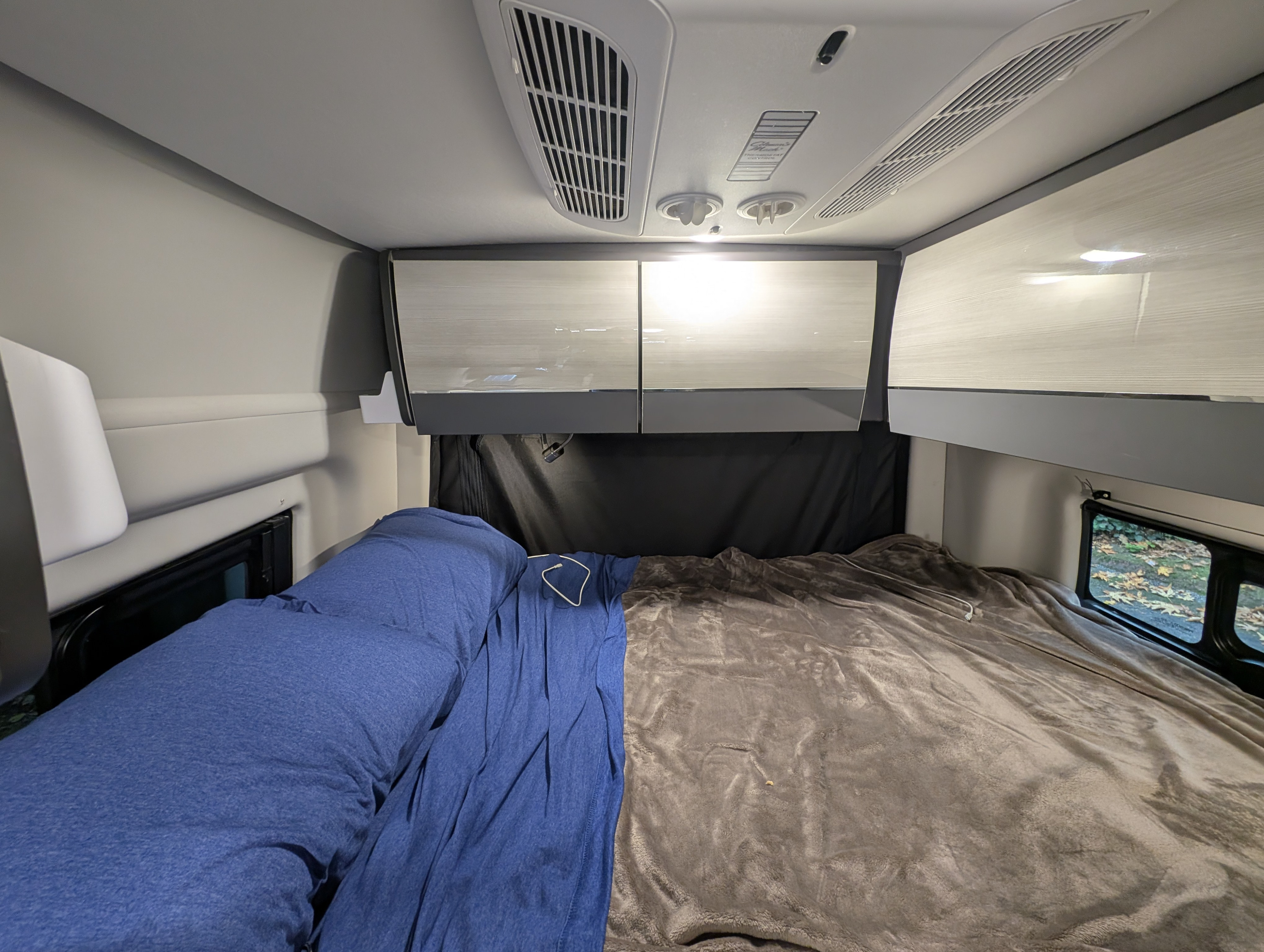 Cozy RV rental bedroom with a comfy bed, overhead storage, and ceiling ventilation. Perfect for a road trip.. Thor Tranquility 2022