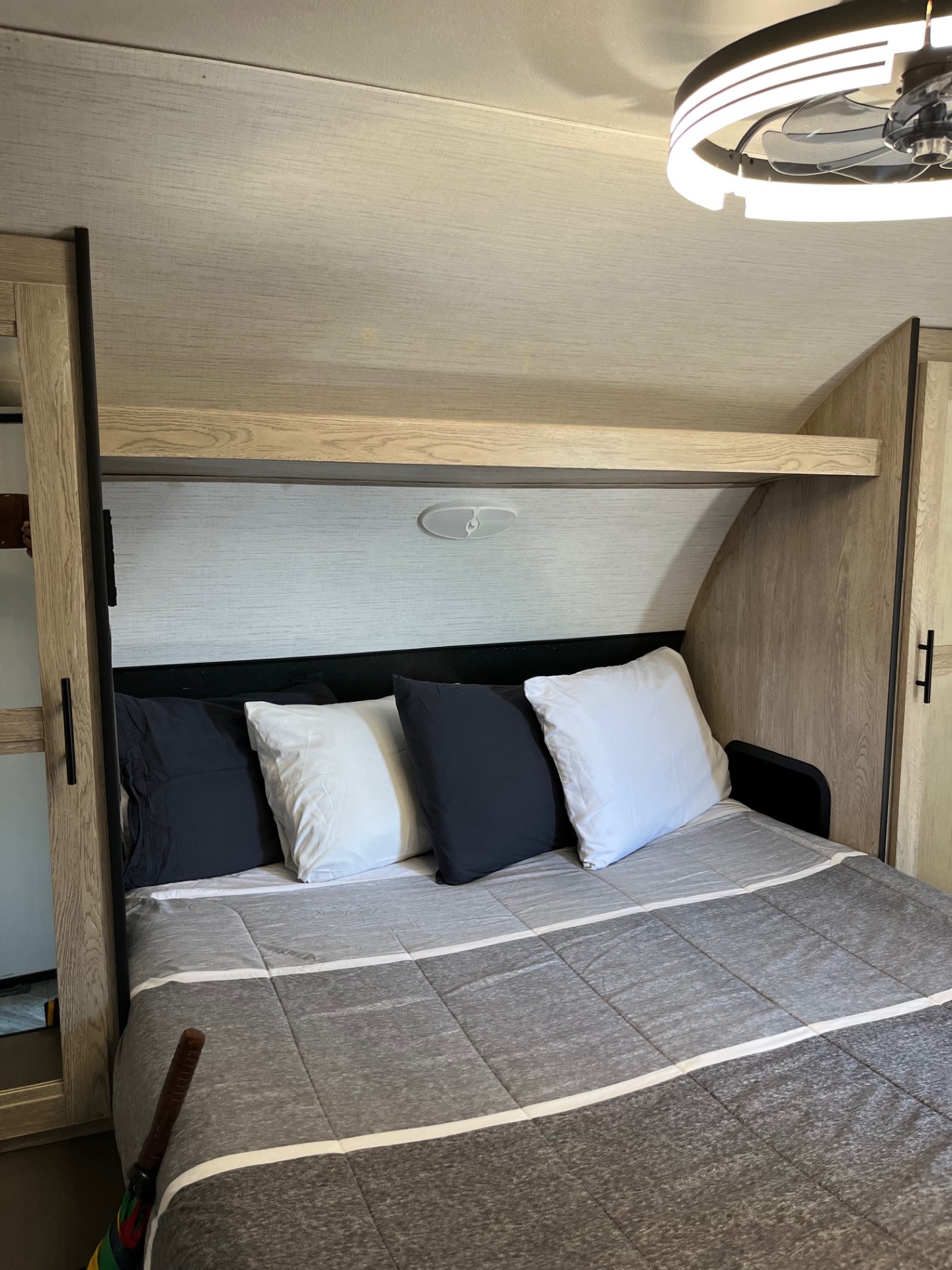 Modern RV rental bedroom: cozy bed with gray/white comforter, pillows, and overhead fan. Perfect for your trip.. Heartland RVs Prowler 2022