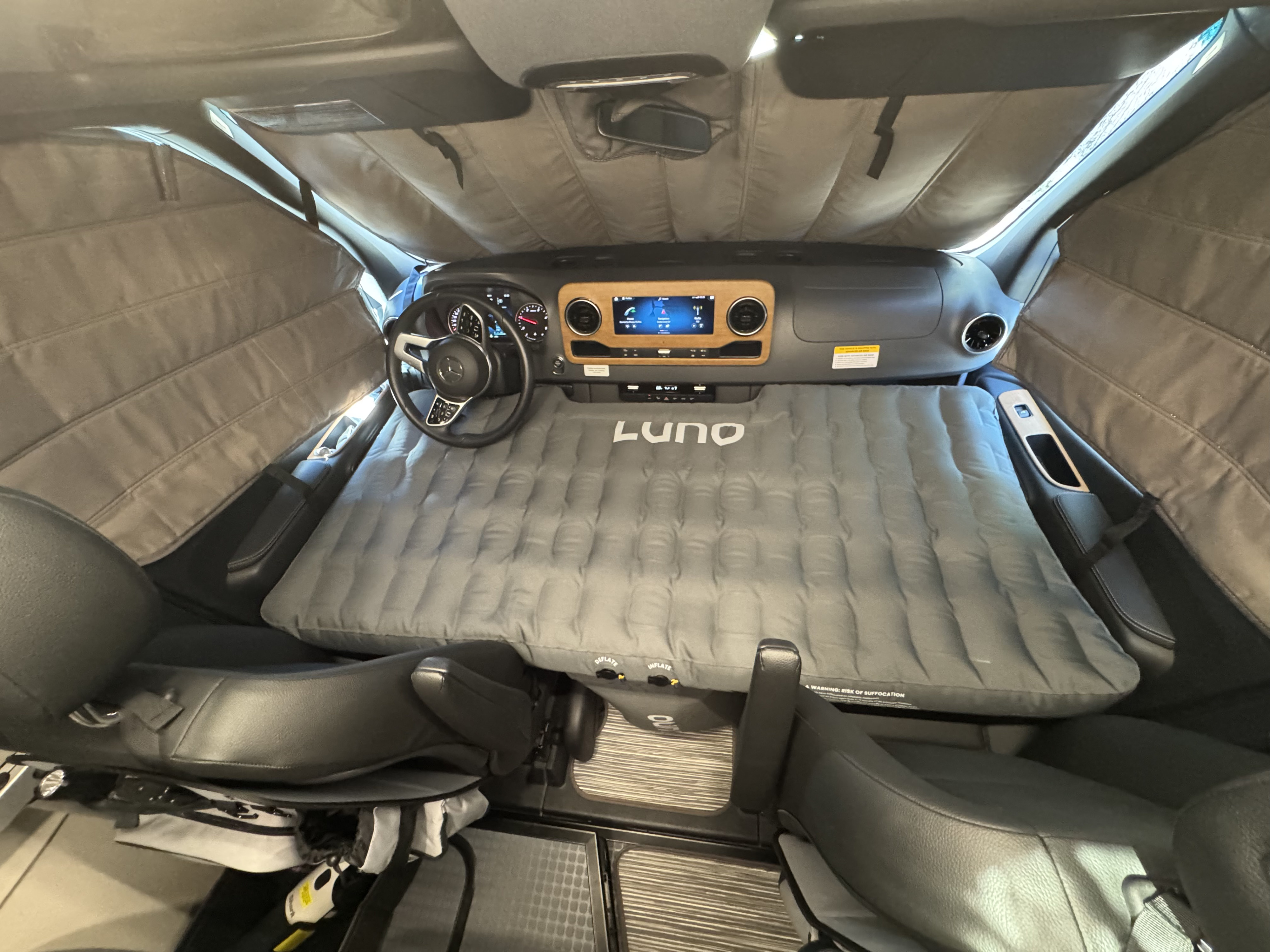 RV rental interior: A LUNO inflatable mattress fills the front cabin, surrounded by privacy shades for a peaceful night.. Winnebago Revel 2025