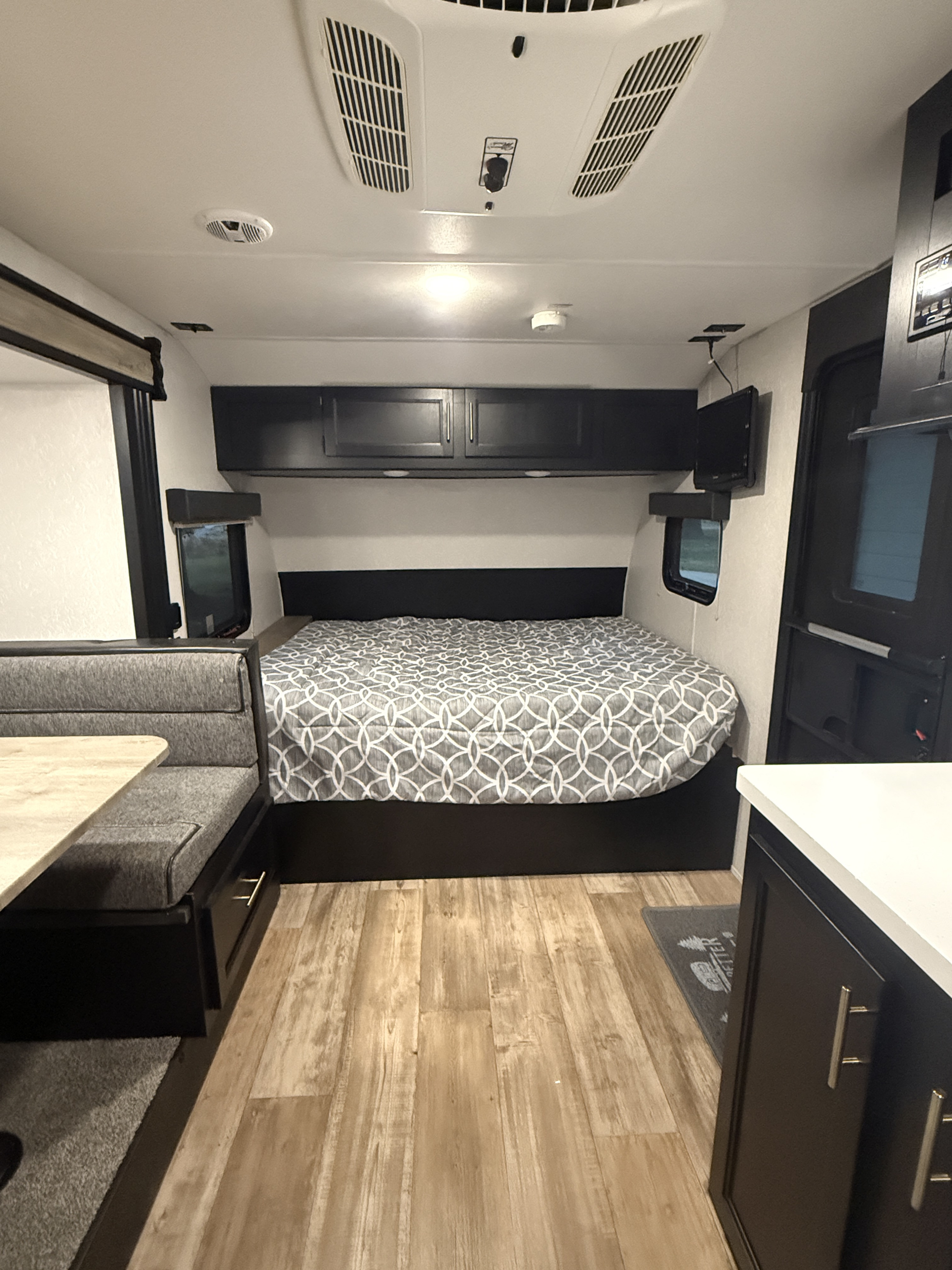 RV rental: A modern camper interior with a bed, dinette, and small kitchen setup, featuring light wood floors.. Forest River Cherokee Wolf Pup Black Label 2021