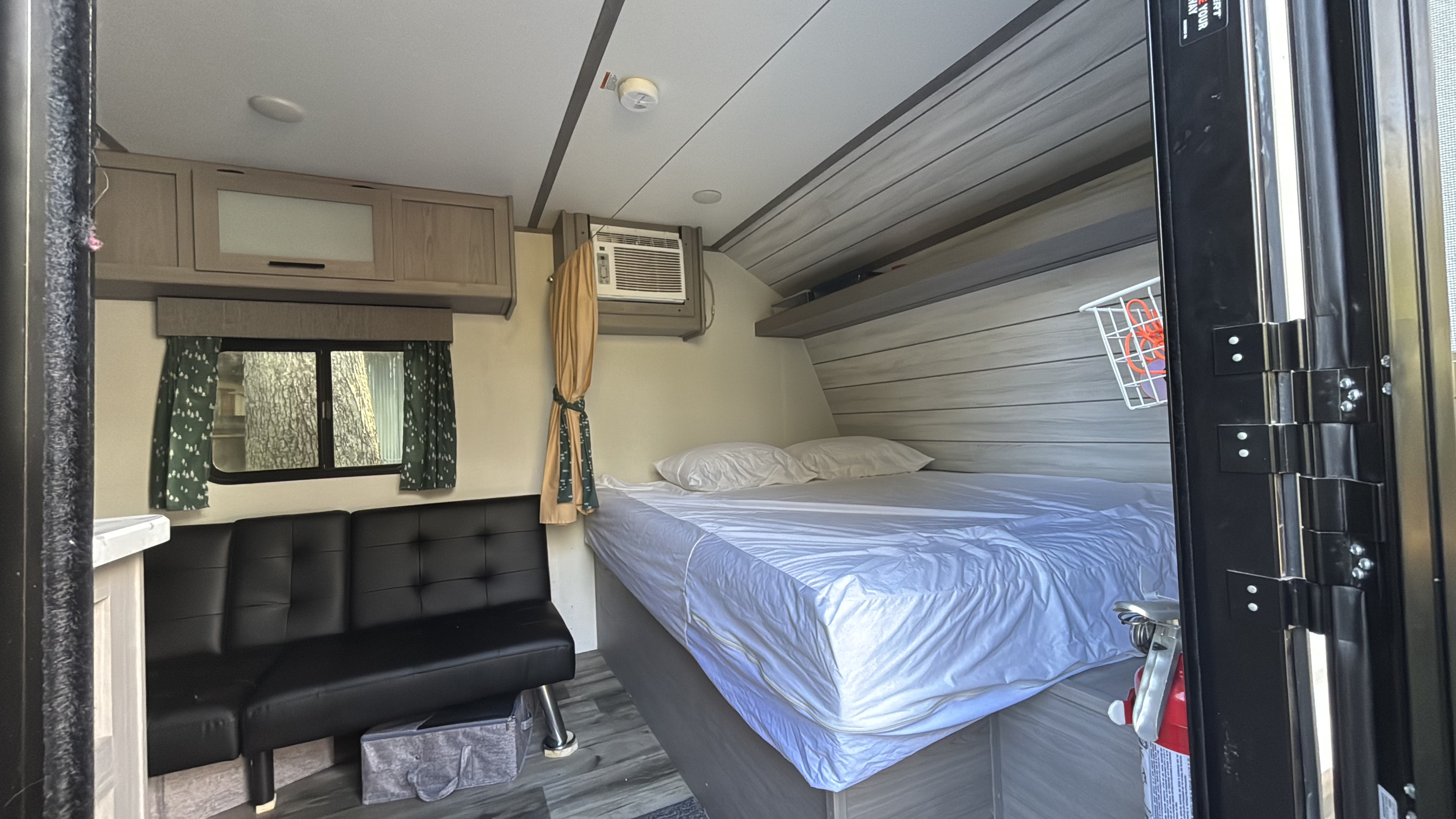 This rv rental offers a compact living space with a comfy bed, futon, AC unit, and overhead cabinets for storage.. Dutchmen Coleman Lantern LT 2023