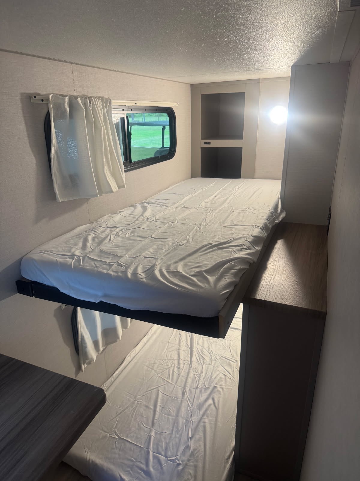Inside an RV rental: a cozy bunk bed setup with upper and lower beds, window, and integrated storage. Ideal for travel.. Forest River Vibe 2024