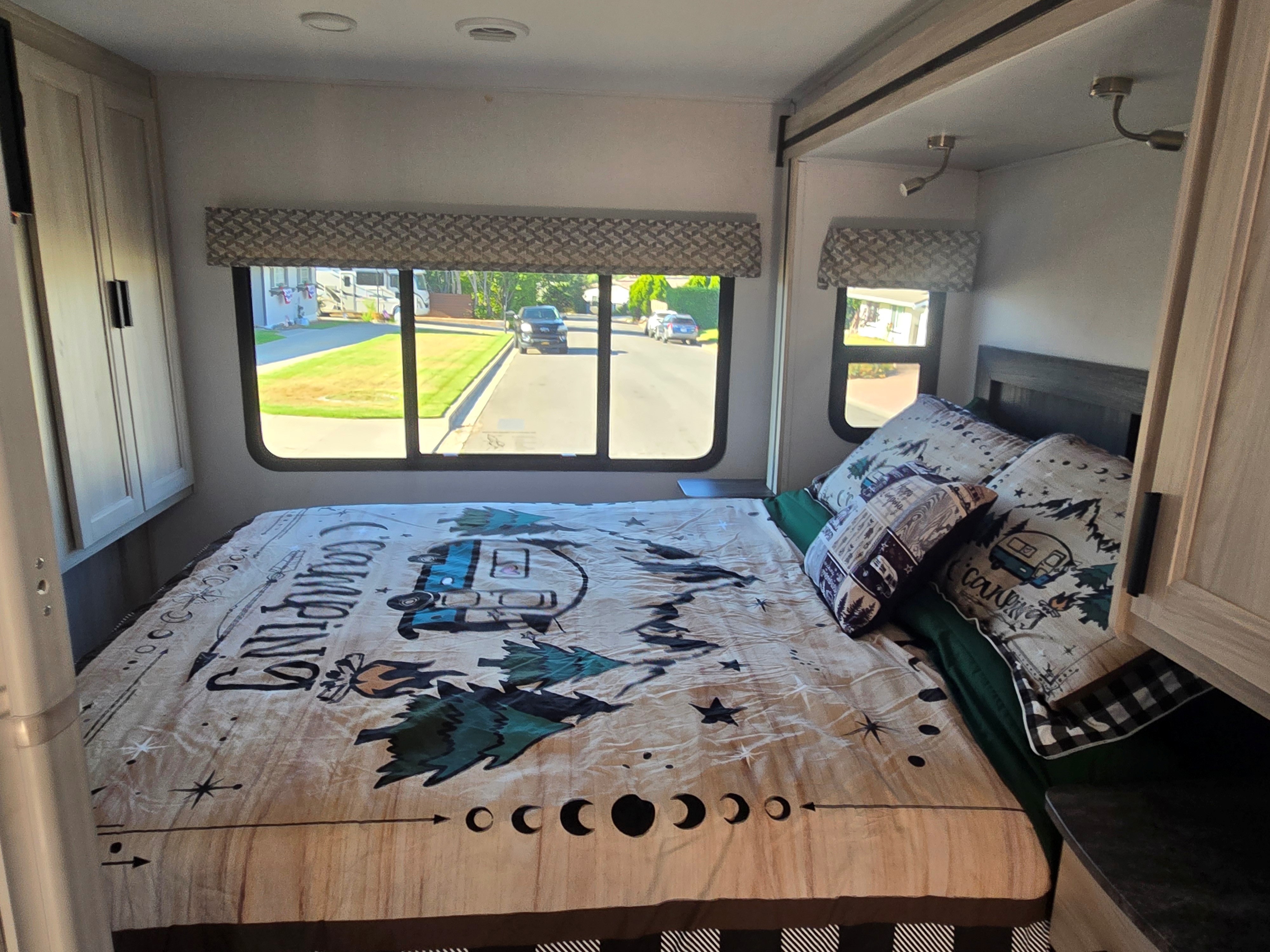 Cozy RV rental bedroom with camping-themed bedding, windows, and storage cabinets.. Forester Classic 2023