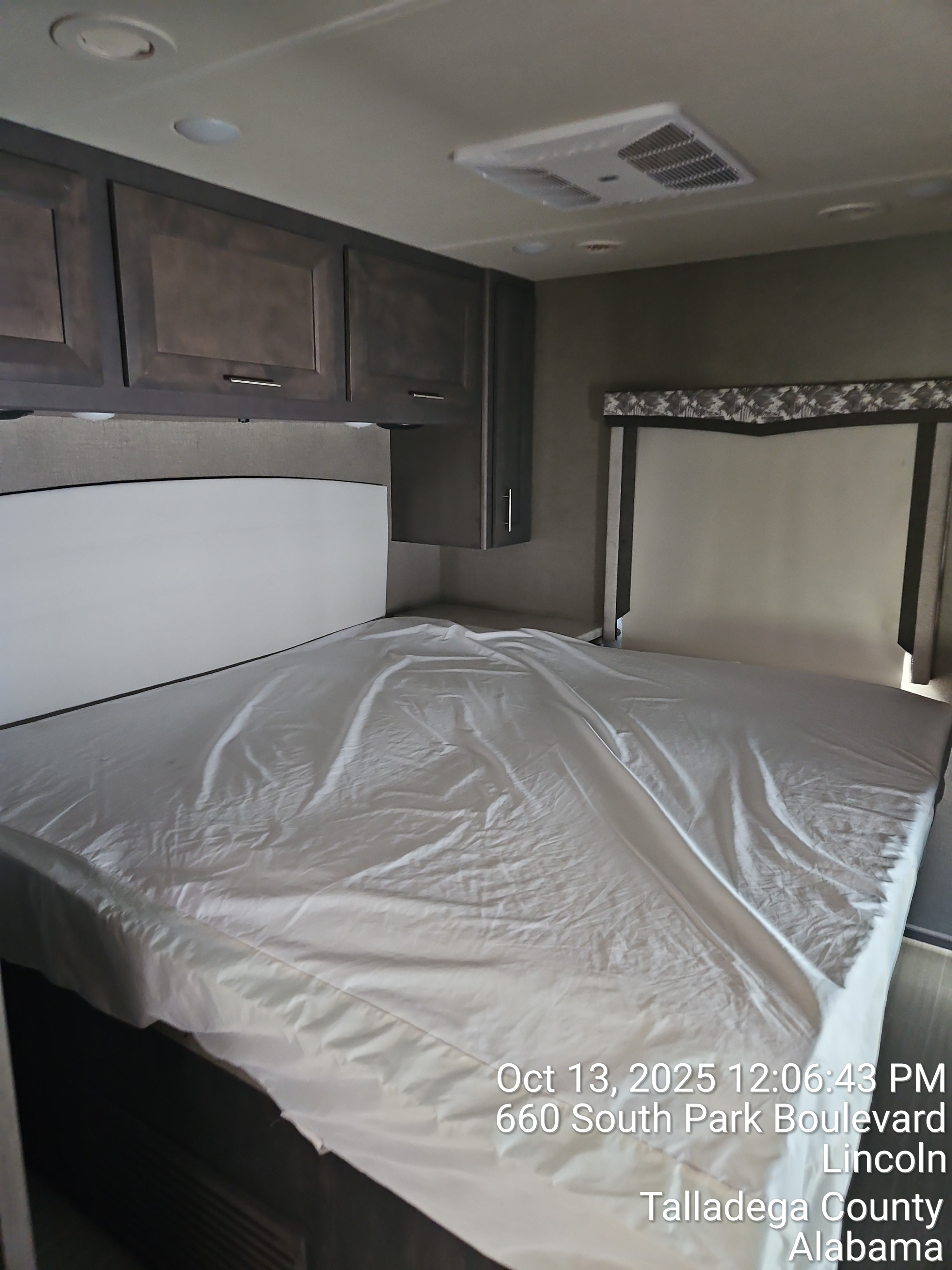 RV rental bedroom showcasing a white bed, dark overhead cabinets, and ceiling AC unit.. thor Magnitude 2025