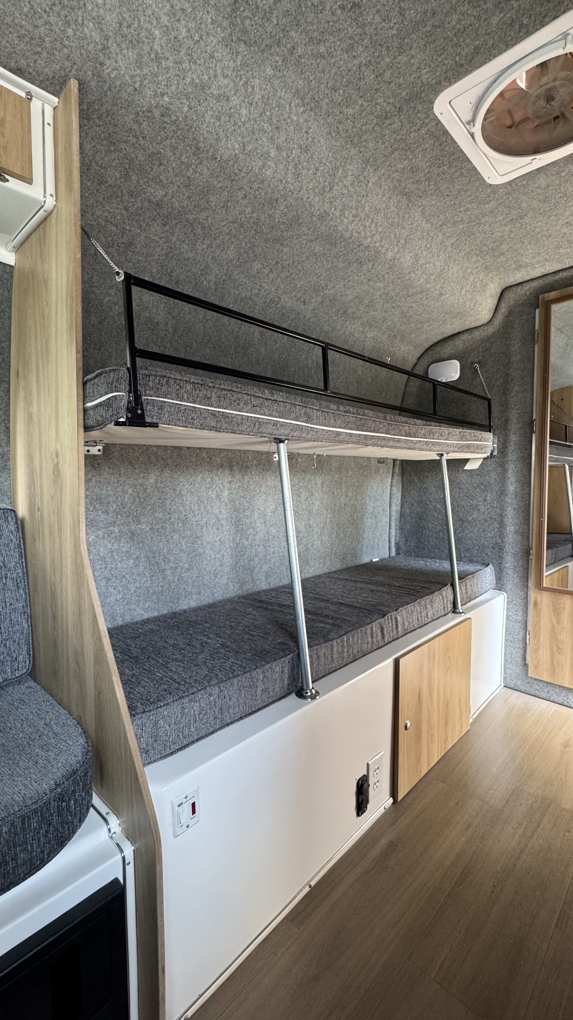 Cozy RV rental interior featuring bunk beds with gray cushions, felt walls, and practical storage solutions.. Casita Casita Heritage Deluxe! 2025
