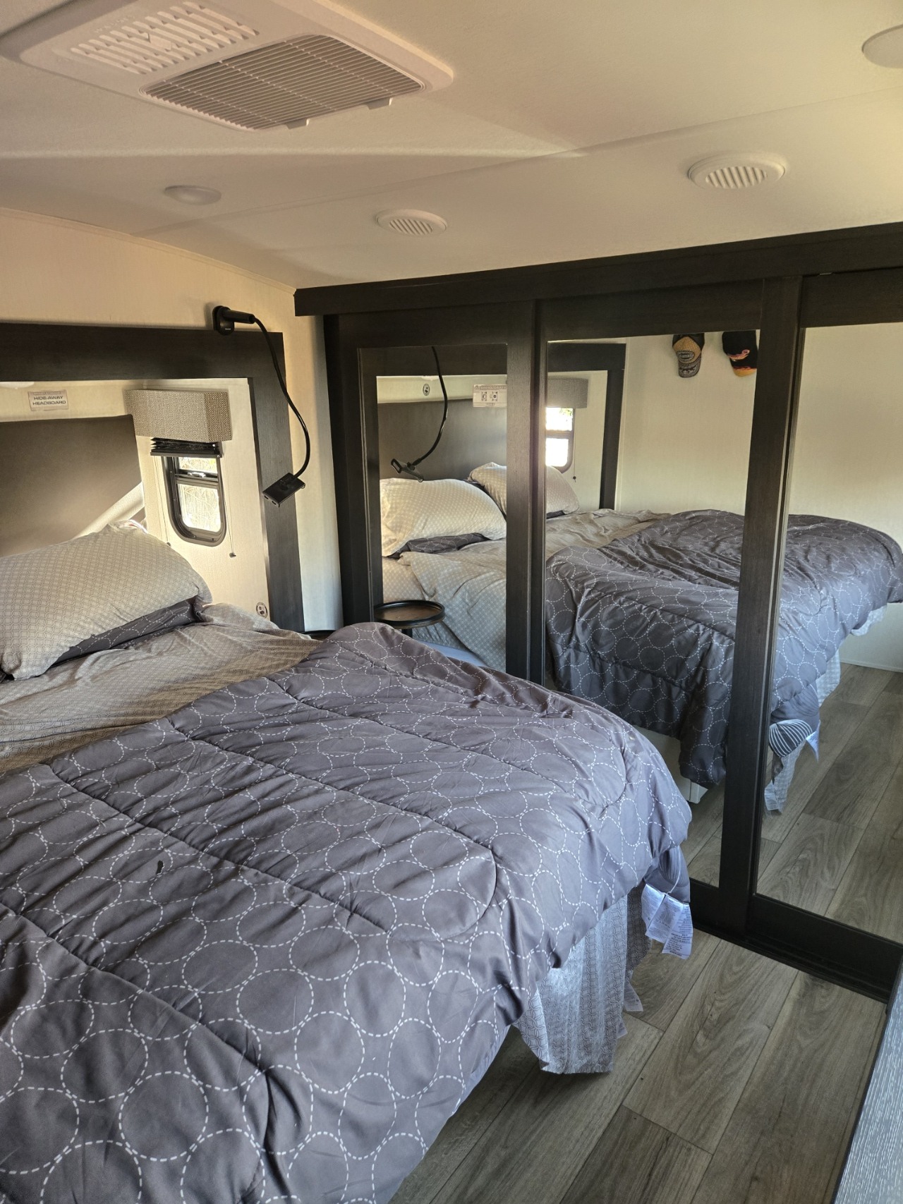 Comfortable RV rental bedroom with a cozy bed, mirrored wardrobe, ceiling AC, and window.. Forest River Sabre 2025
