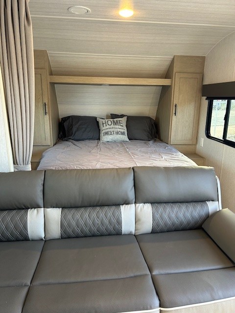 Cozy RV rental interior featuring a comfortable bed with a "HOME SWEET HOME" pillow and a modern living area sofa.. Forest River Salem Cruise Lite 2024