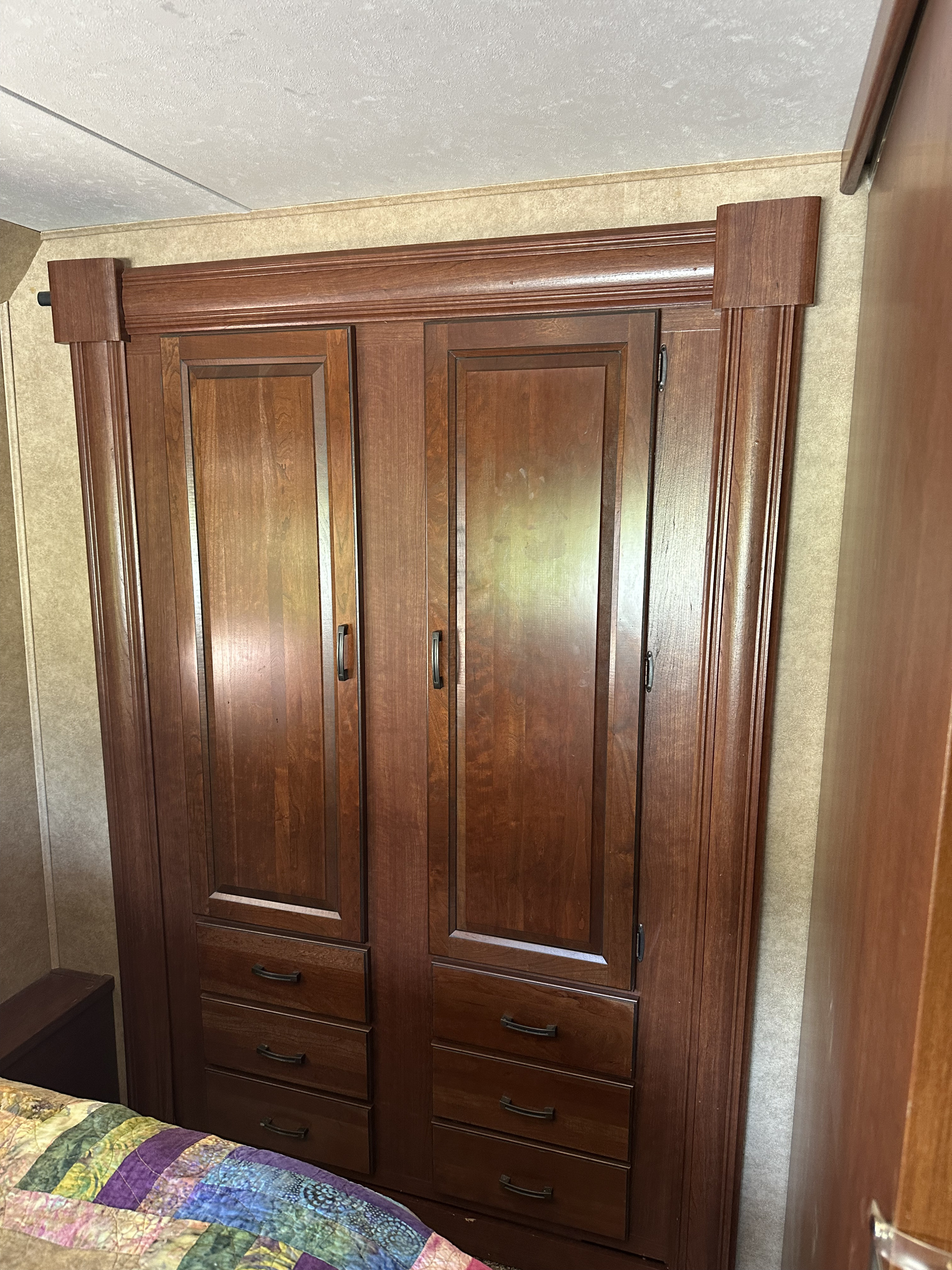 Dark wood wardrobe with cabinet doors and drawers inside an RV rental, offering practical storage.. Forest River Sunseeker 2014